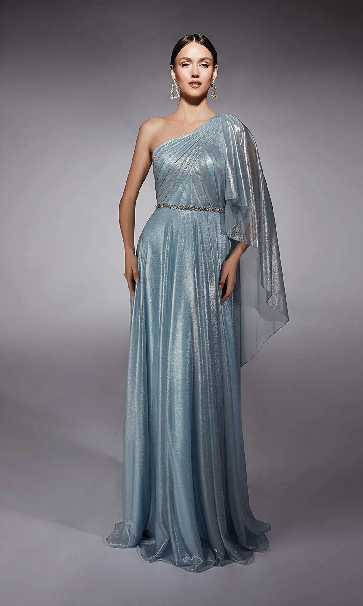 A woman wears the Alyce 27719 long formal dress in light blue, featuring a one-shoulder design, sheer fabric, and a belted waist, while standing against a plain gray background.