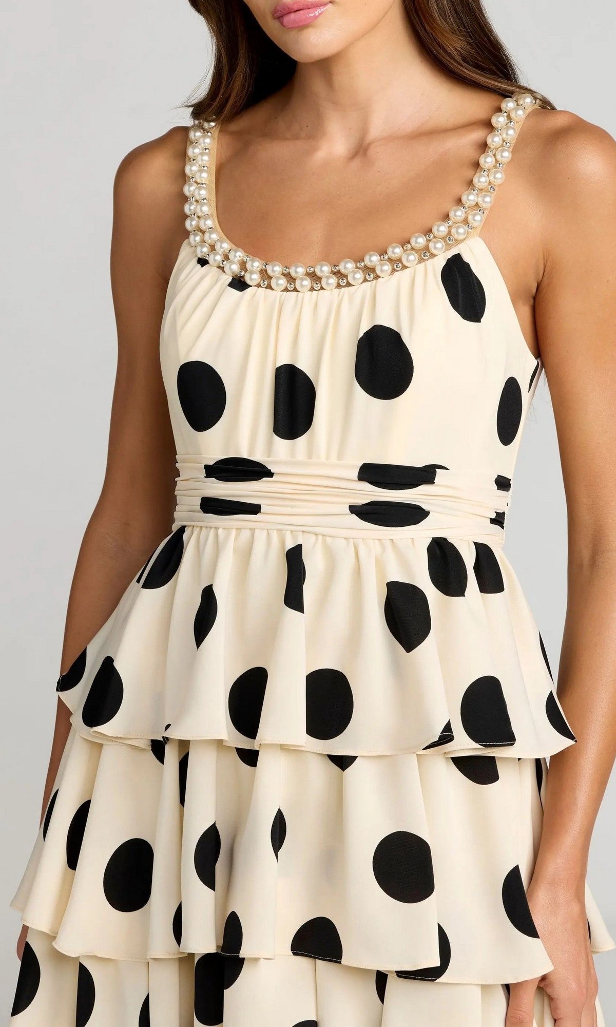 A woman wears the Mac Duggal 27736 Midi Party Dress, featuring an ivory polka-dot pattern, a pearl-trimmed neckline, and layered ruffles that capture a playful yet sophisticated style.