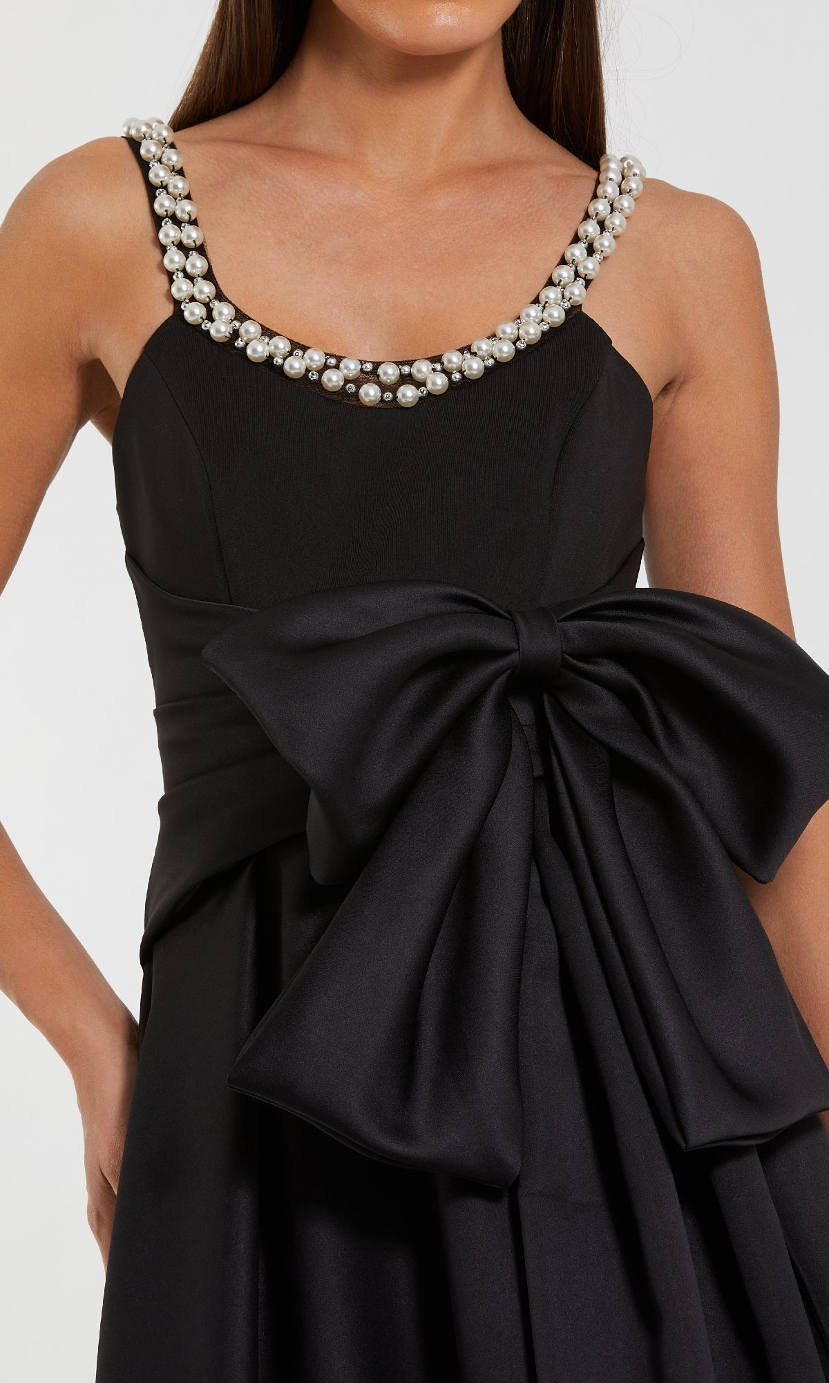 Black dress with pearl embellishments on a plain background