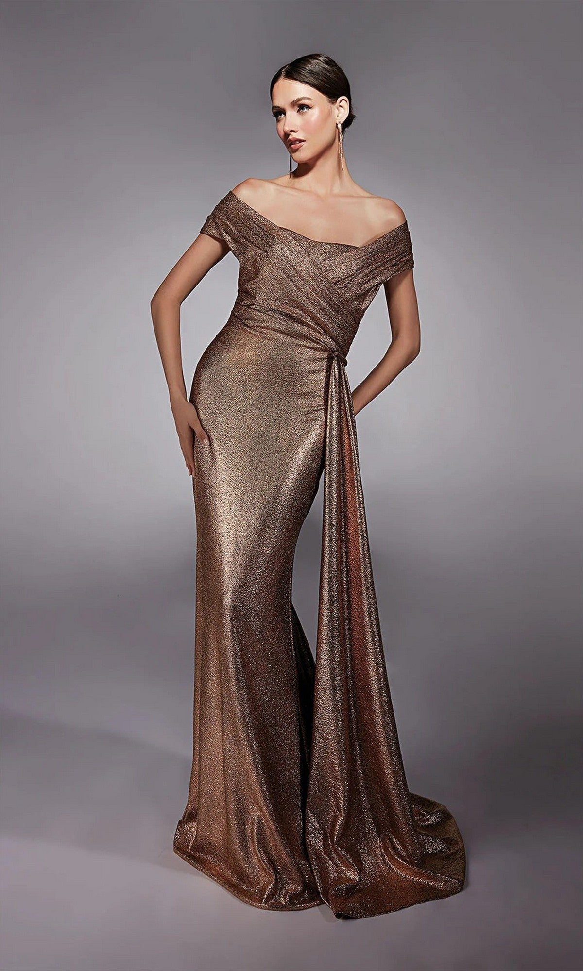 A woman poses gracefully against a plain gray background in the Alyce 27767 long formal dress, featuring shimmering rose gold jacquard fabric with an off-the-shoulder neckline and draped sash.