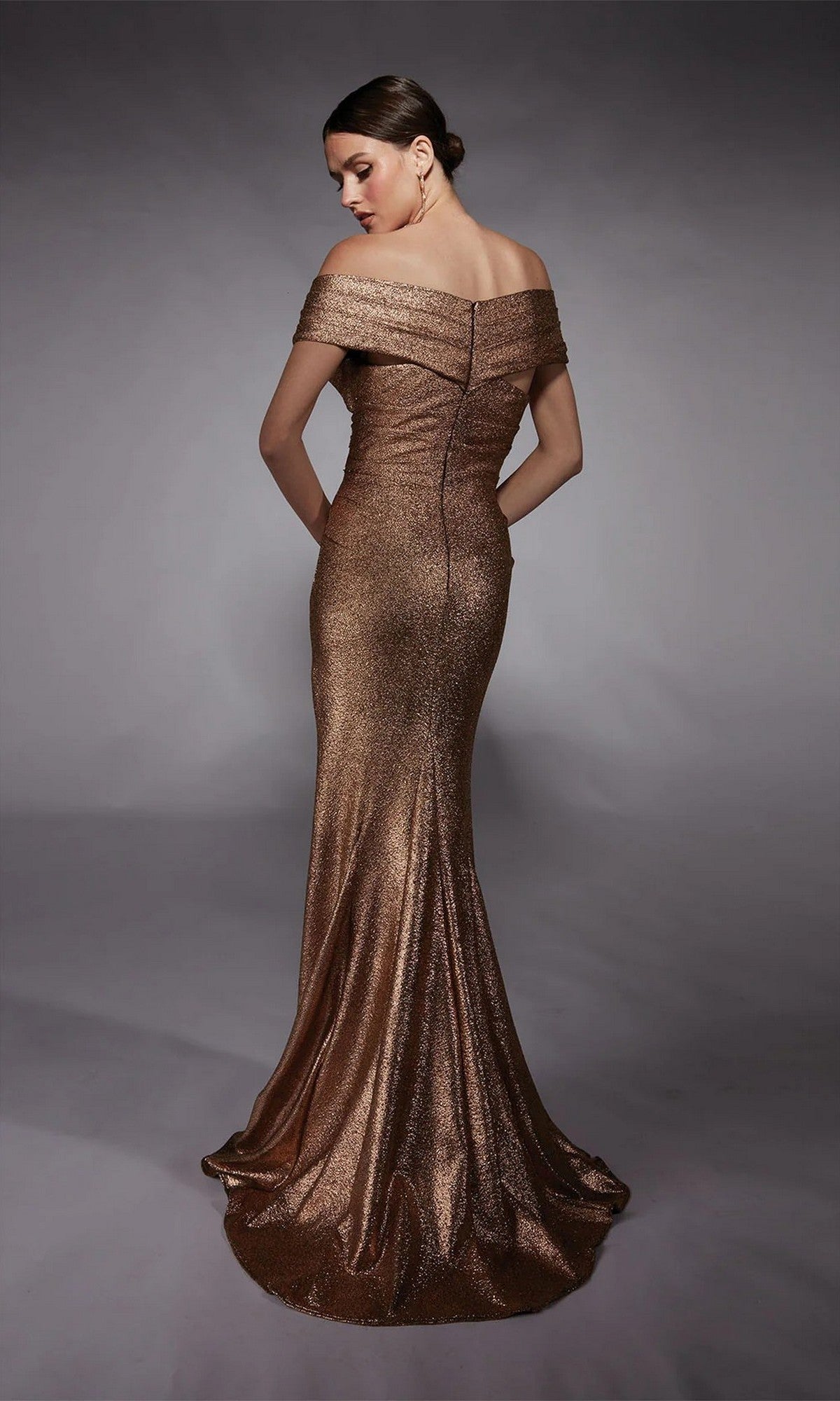 Model in the Alyce 27767 Long Formal Dress, an off-the-shoulder metallic bronze gown with a fitted bodice and flared train, poses against a neutral gray background.