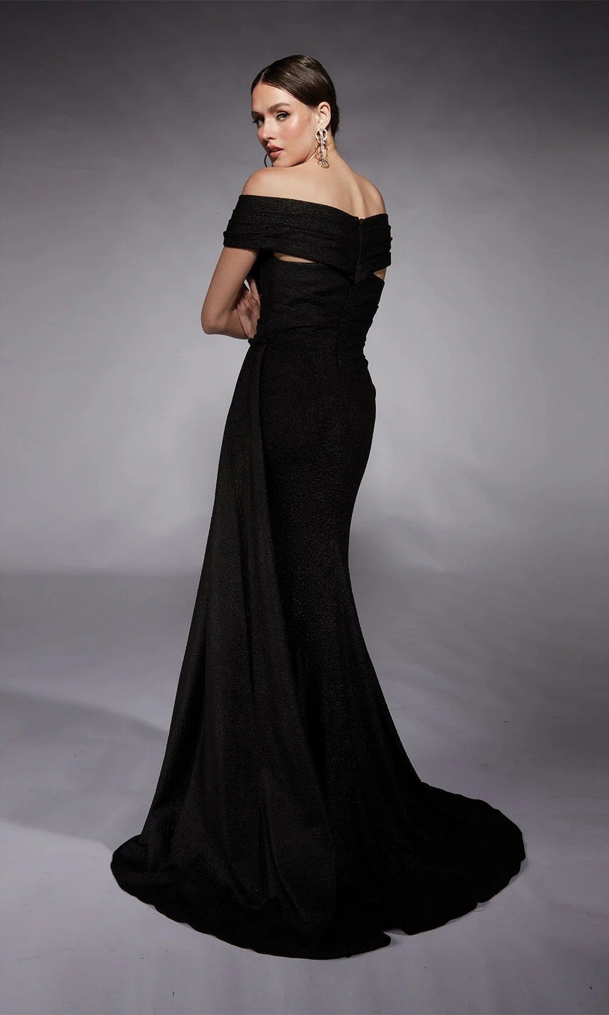A woman models the Alyce 27767 long formal dress—a floor-length, off-the-shoulder gown with a fitted bodice and flared skirt—against a gray background, perfect as an elegant mother-of-the-bride choice.