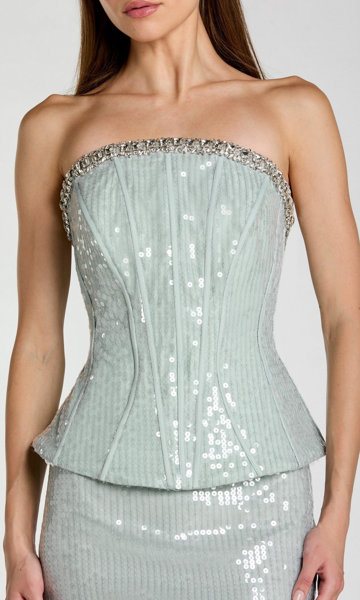 A woman wears the Mac Duggal 27776 long formal dress, featuring a strapless pale blue sequined corset bodice with ornate beading along the neckline and structured boning details, paired with a matching skirt for an elegant look.