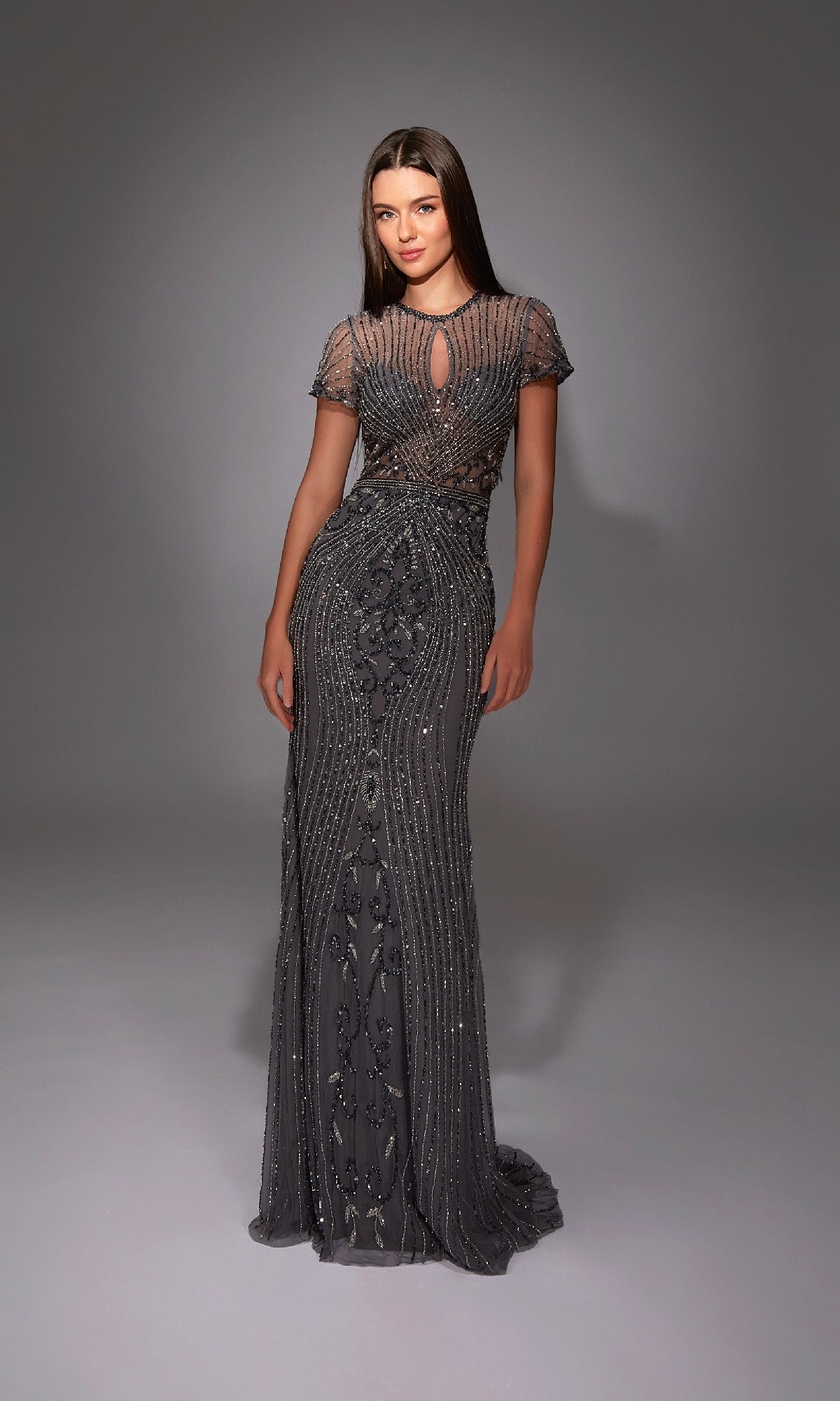 A woman wears the Alyce 27823 long formal dress in dark gray, featuring sheer short sleeves, intricate beading, and a keyhole neckline—a stunning choice for special occasions.