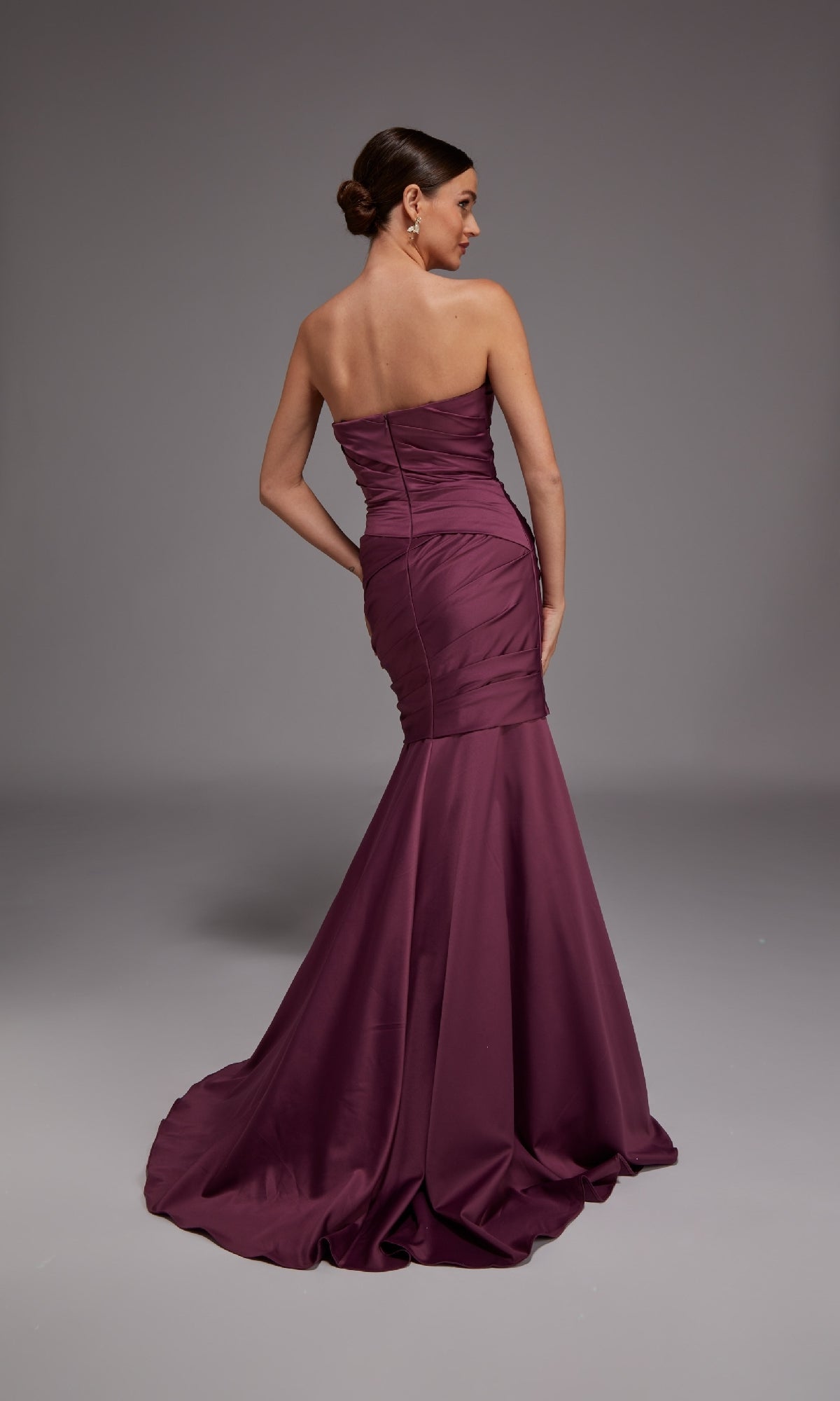 A woman poses in the Alyce 27836 long formal dress—strapless, with a sweetheart neckline and mermaid skirt—in burgundy, flowing elegantly to the floor against a plain gray background.