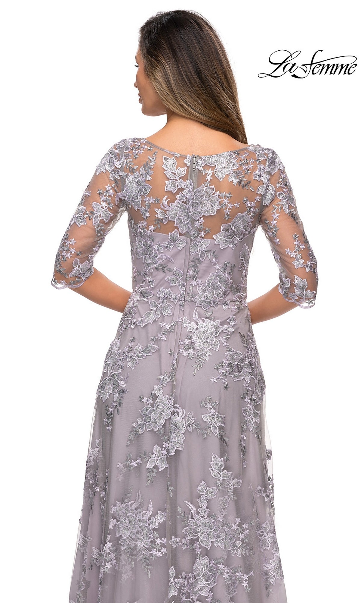 Woman wears Long Formal Dress: La Femme 27854—lavender lace with floral patterns, half sleeves, sheer upper, and visible back zipper—shown from the back.