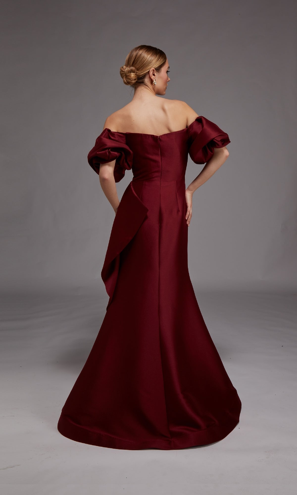 Woman shown from the back wearing the Alyce 27863, a floor-length burgundy off-the-shoulder formal dress with puffed sleeves and a fitted silhouette, against a plain gray background.