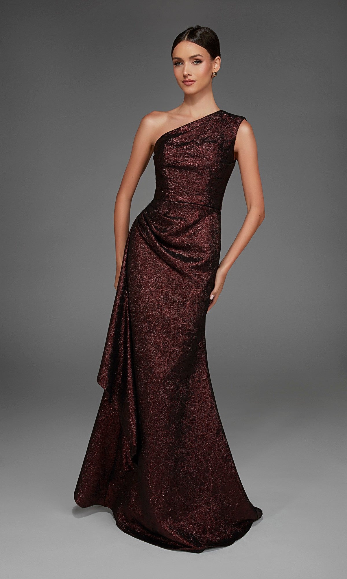 A woman poses against a plain gray background wearing the Alyce 27885 long formal dress, a floor-length, one-shoulder evening gown in dark red with elegant draped detailing.