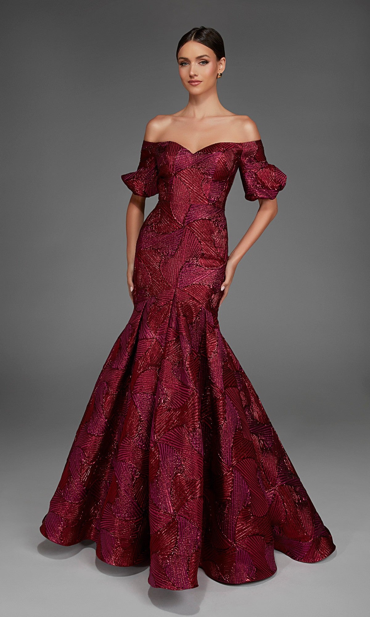 A woman poses against a gray backdrop wearing the Alyce 27889 long formal dress in wine, featuring an off-the-shoulder sweetheart neckline, fitted silhouette with a jacquard textured pattern, mermaid skirt, and short puffed sleeves.