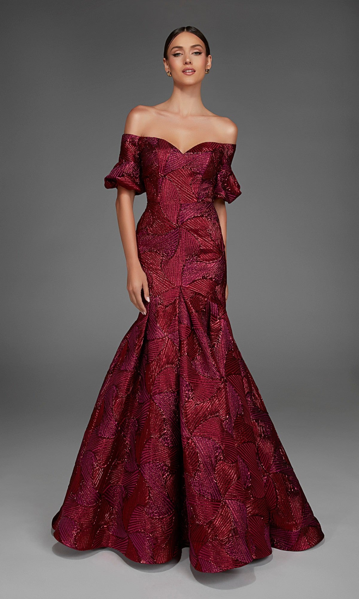 A woman stands against a plain gray background wearing the Alyce 27889 long formal dress, featuring an off-the-shoulder sweetheart neckline, short sleeves, a flared skirt, and crafted in floor-length burgundy jacquard.