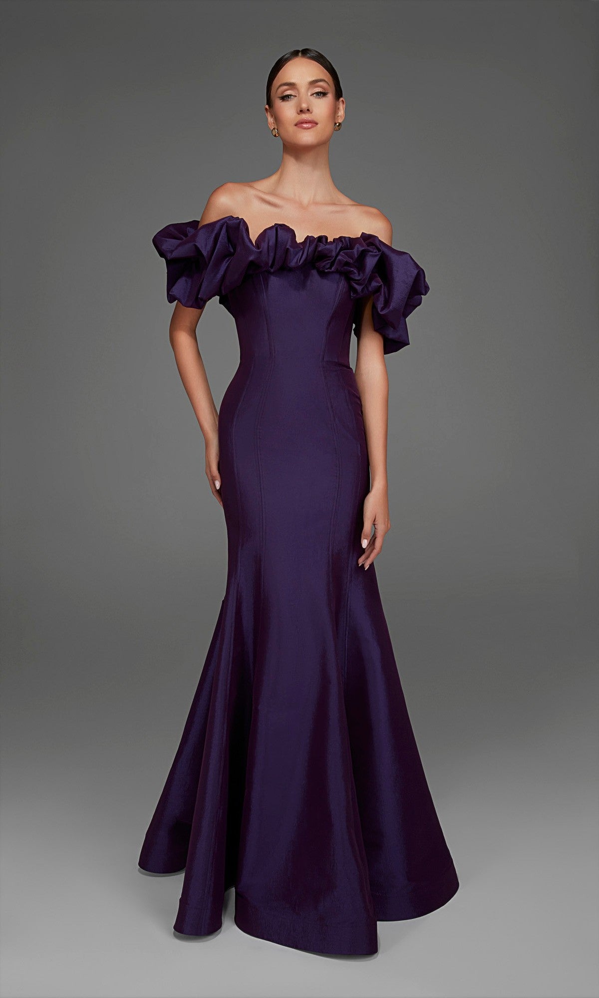 A woman wearing the Alyce 27895 long formal dress in plum, featuring an off-the-shoulder ruffled neckline and a subtle mermaid skirt, poses against a plain gray background.