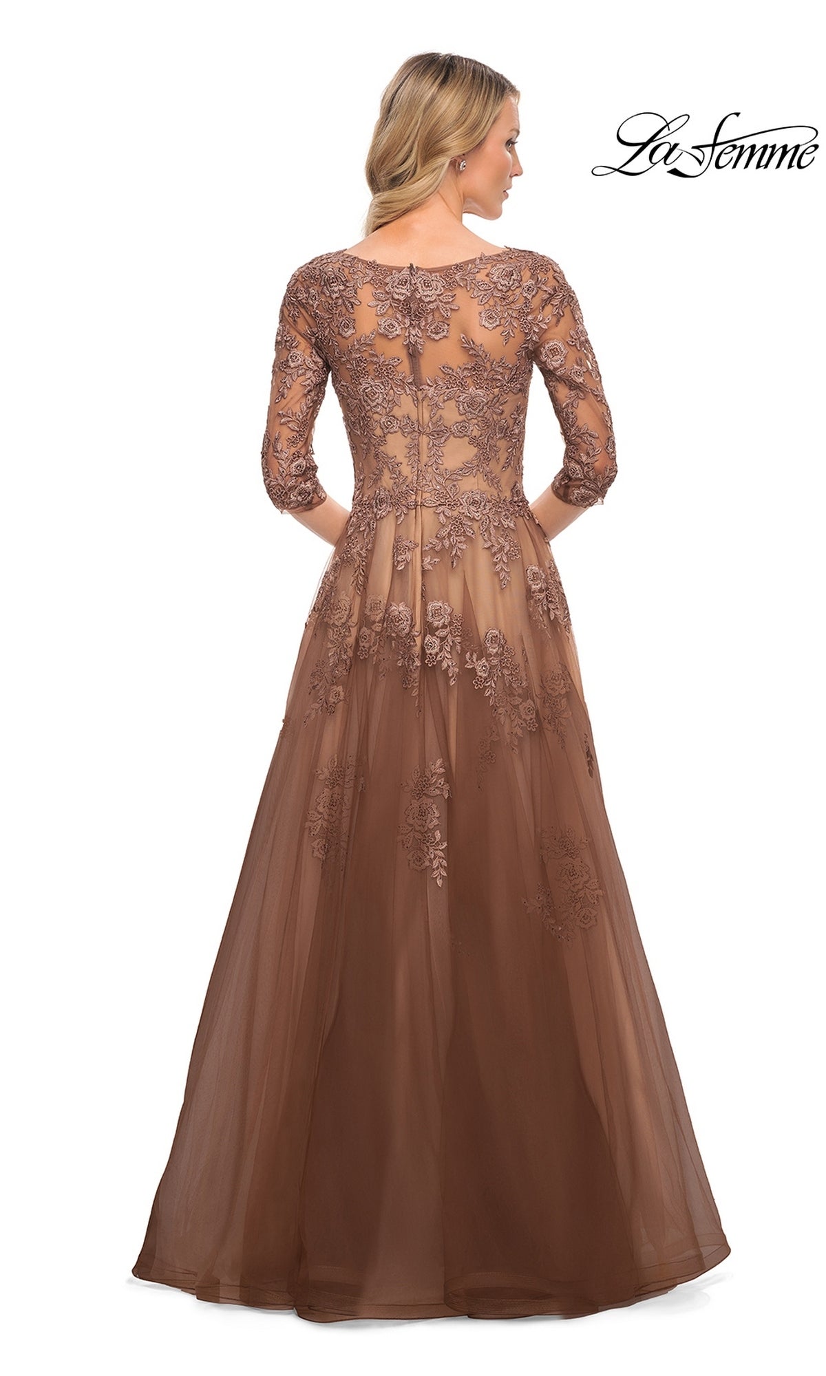 A woman wears a brown lace Long Formal Dress: La Femme 27908 with three-quarter sleeves and floral embroidery over a sheer bodice.