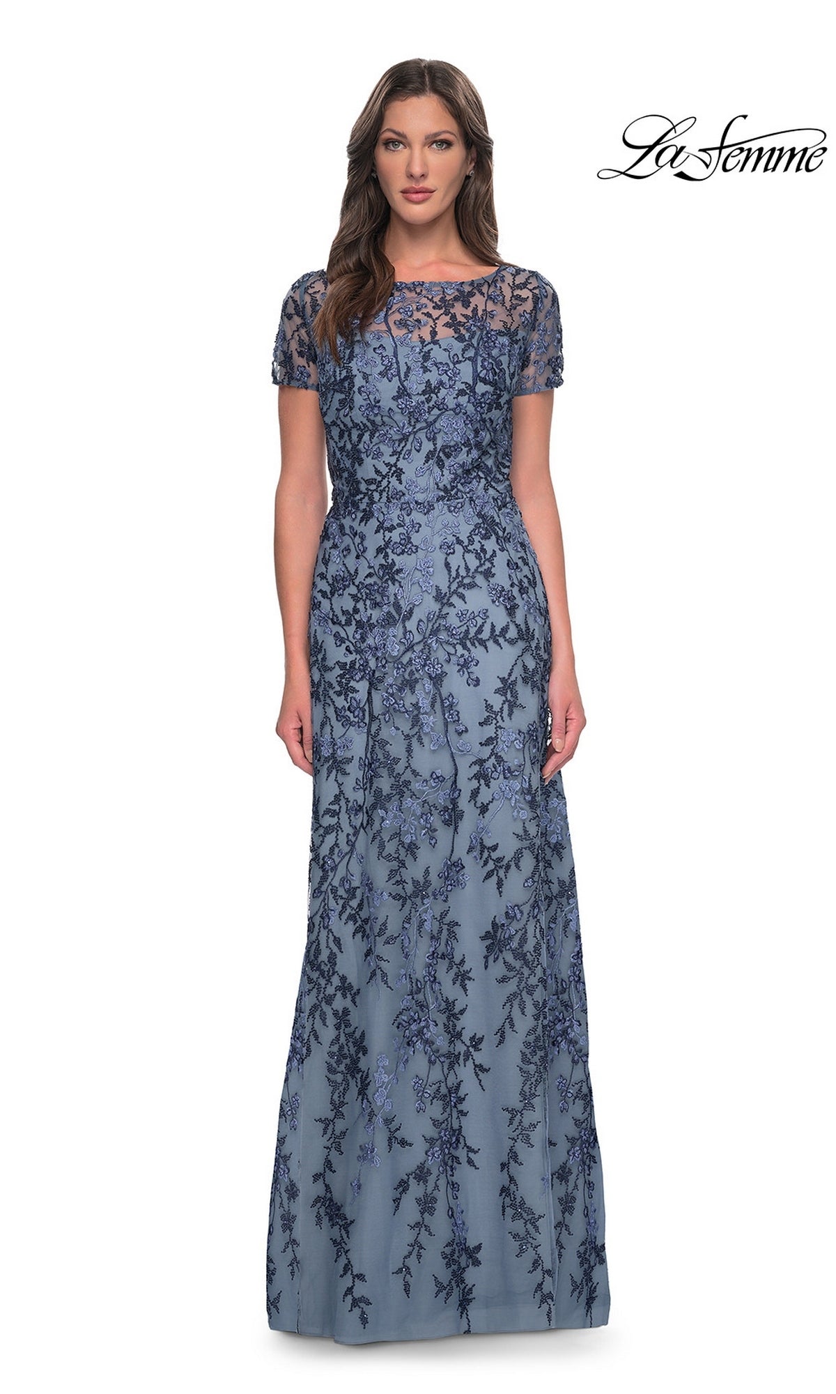 Woman wearing Long Formal Dress: La Femme 27956 in slate, a floor-length, short-sleeve lace gown with floral beading, against a white background. “La Femme” logo in the top right.