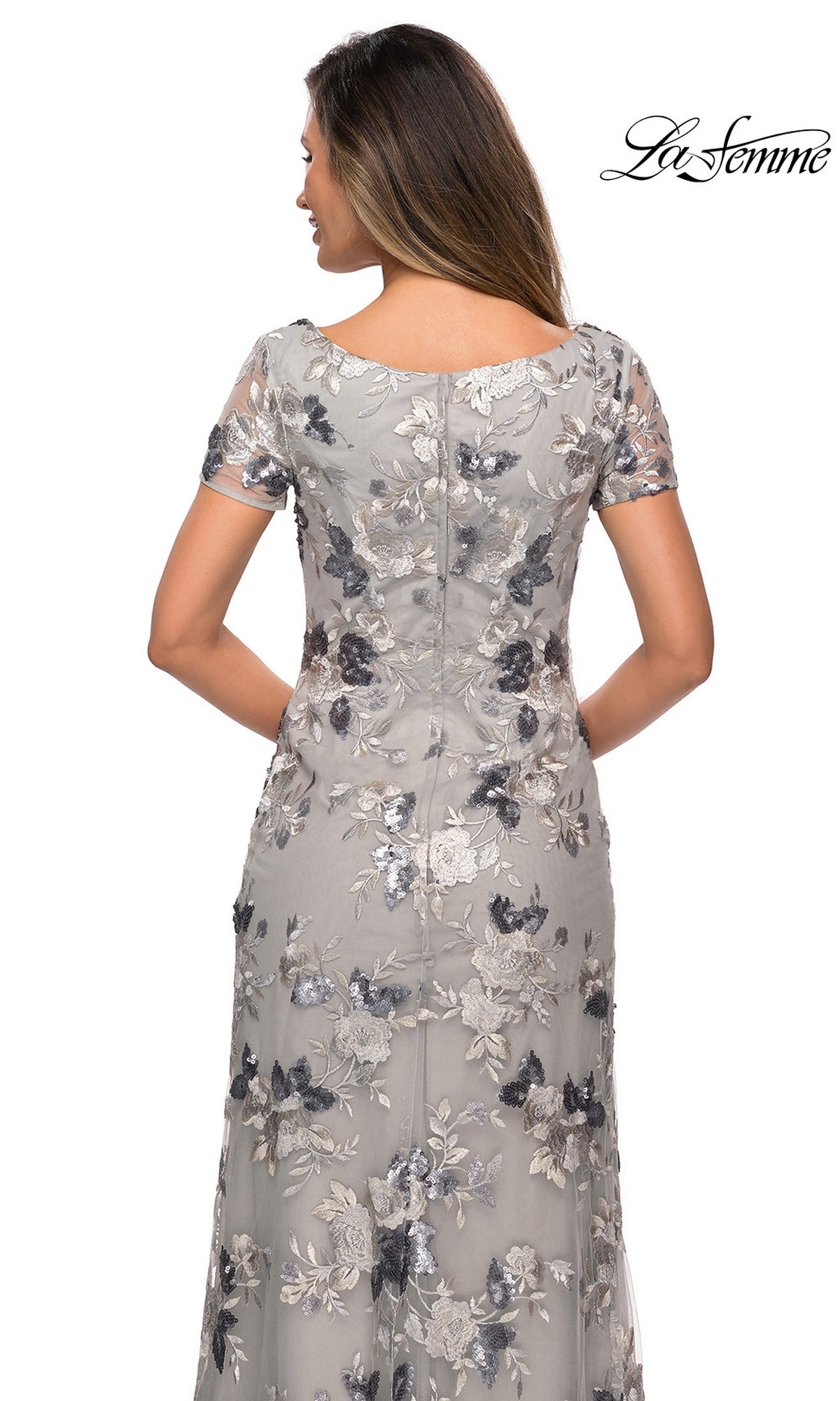 Back view of a woman wearing a La Femme 27991 floor-length silver formal dress with short sleeves and floral sequin embroidery.