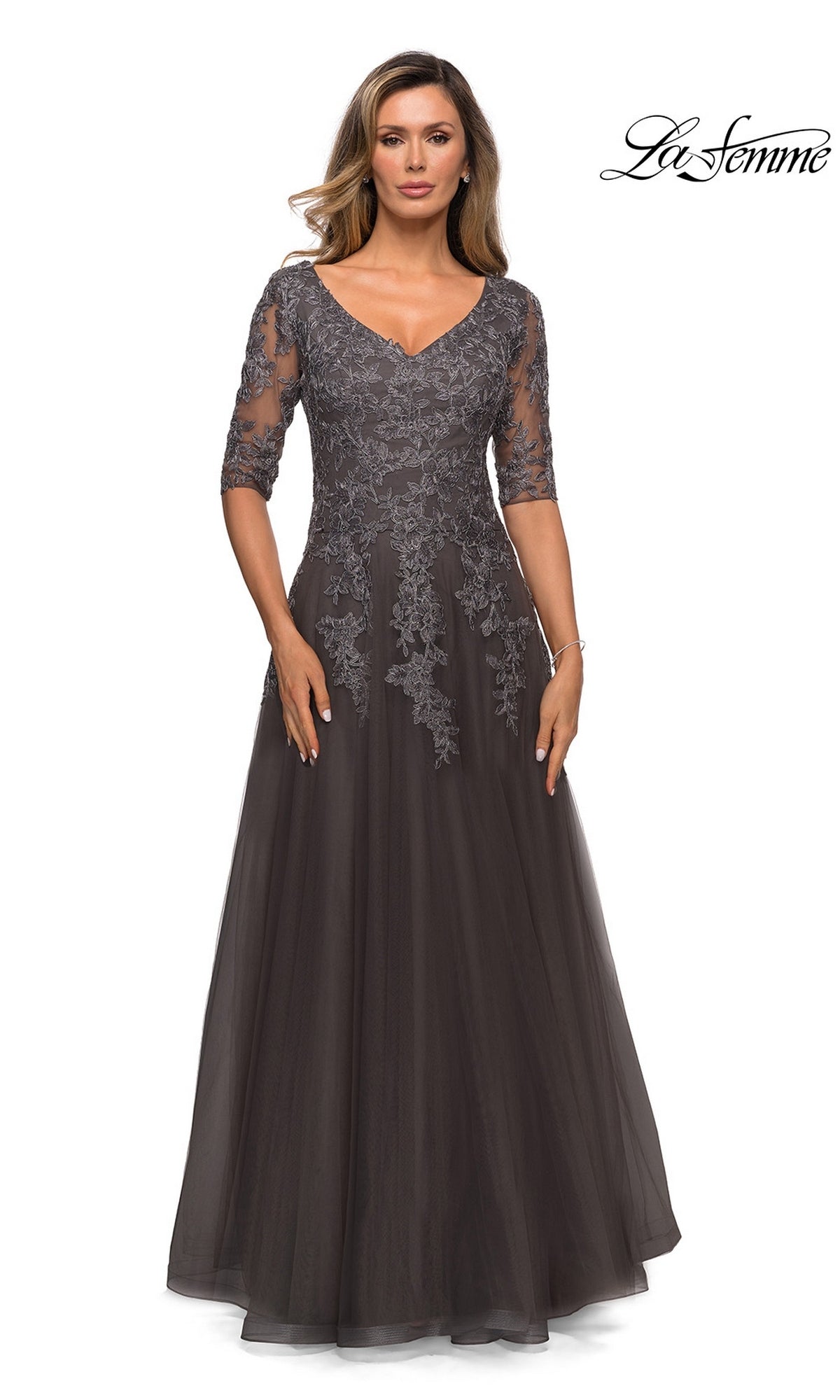 A woman wearing a gunmetal-colored La Femme 27993 A-line formal dress with three-quarter floral lace sleeves and a V-neckline.