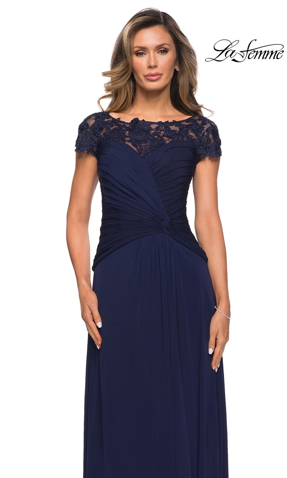 Woman wearing Long Formal Dress: La Femme 28029—navy blue with lace shoulders and upper chest, A-line skirt, and gathered draped waist—against a white background.