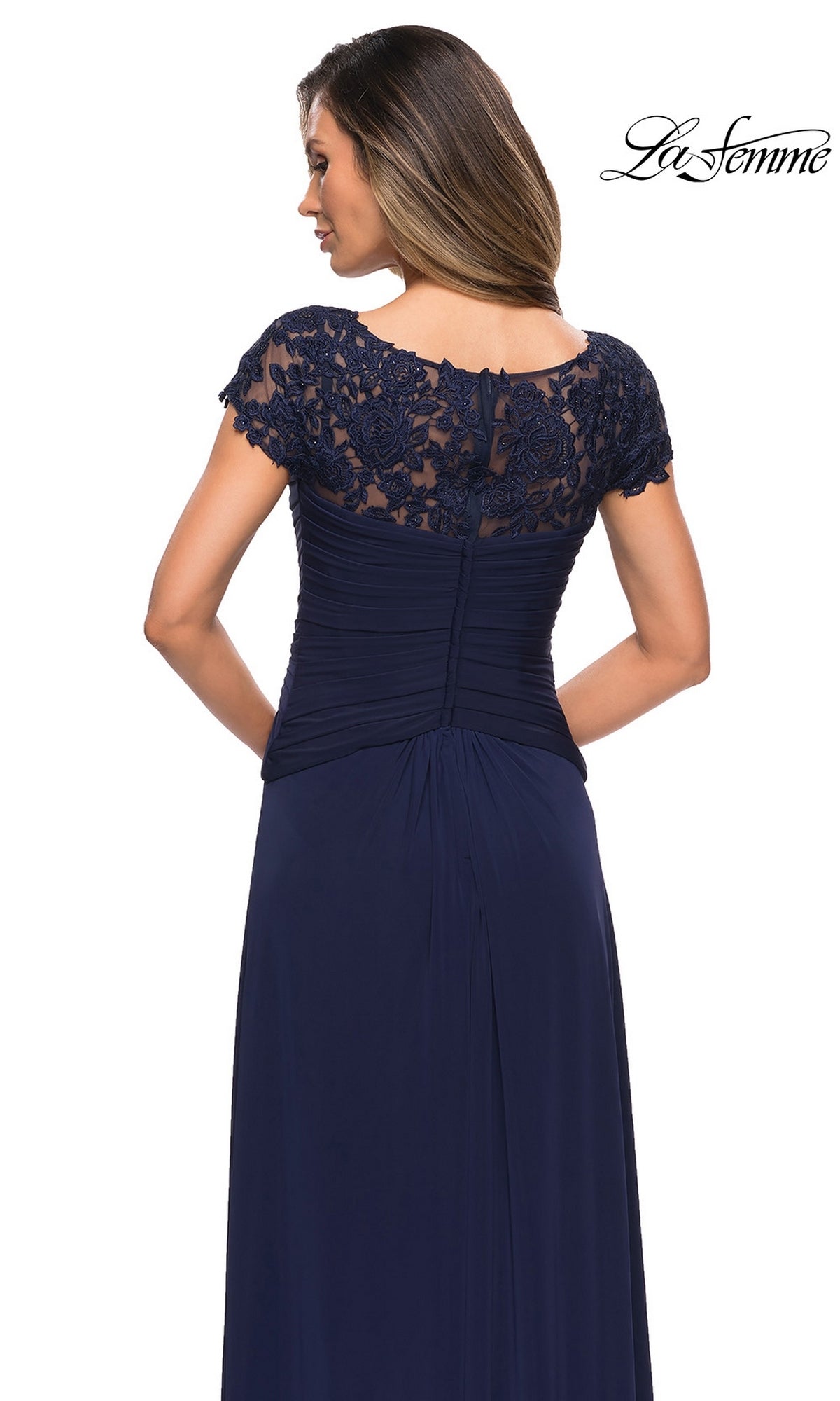 Woman in a navy blue Long Formal Dress: La Femme 28029 with lace cap sleeves, ruched bodice, and A-line skirt. The “La Femme” logo appears in the top right corner.