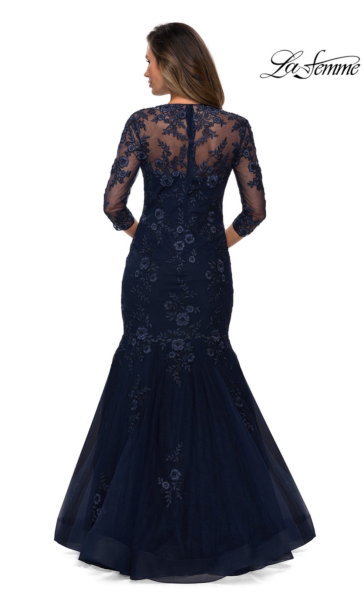 Woman in the Long Formal Dress: La Femme 28033—navy blue floral lace with sheer sleeves, embroidery, and a mermaid silhouette—shown from the back.