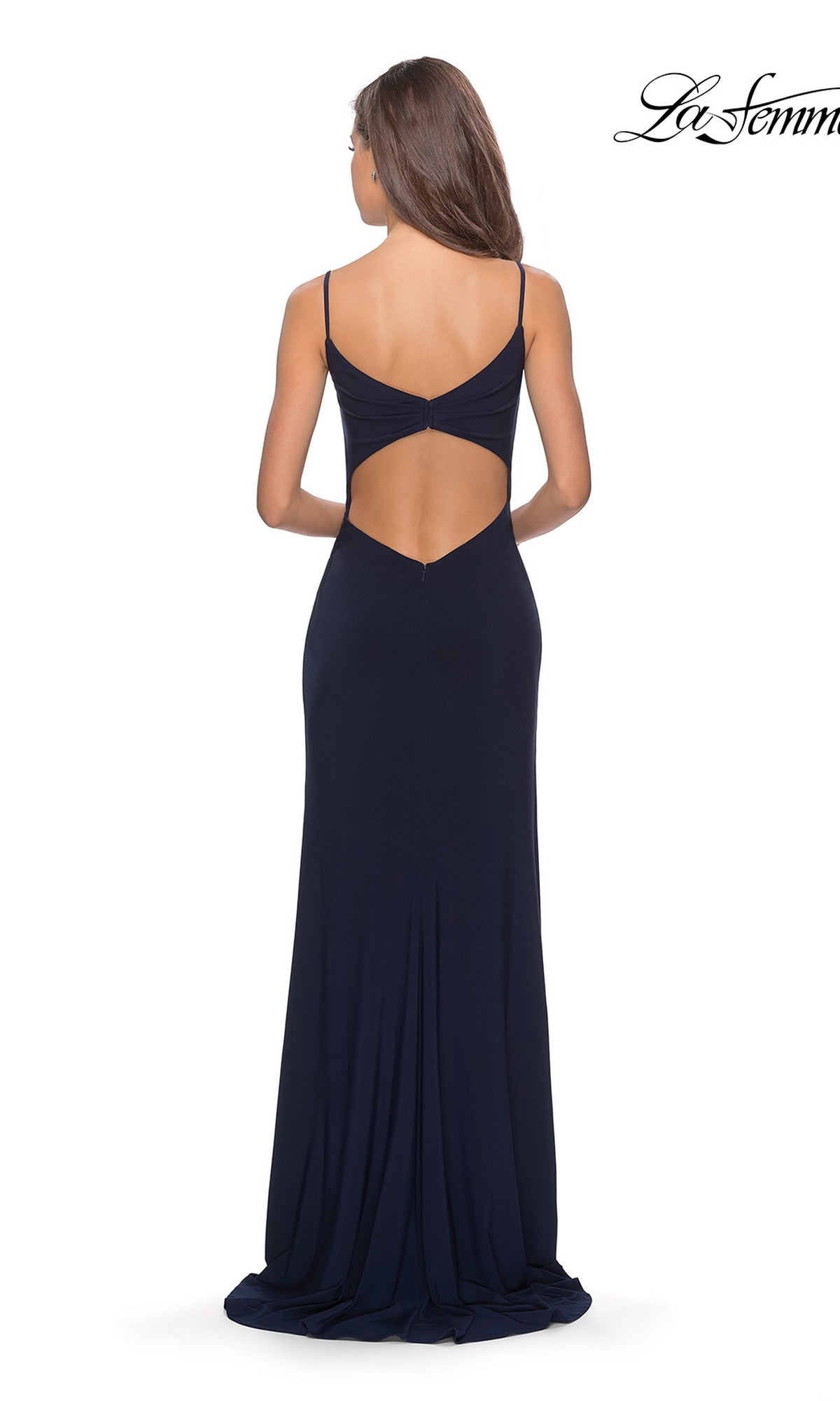 Woman wearing the La Femme 28079 long prom dress in navy blue, featuring thin straps, an open back cutout, and a floor-length jersey skirt with a thigh-high slit, standing facing away from the camera.