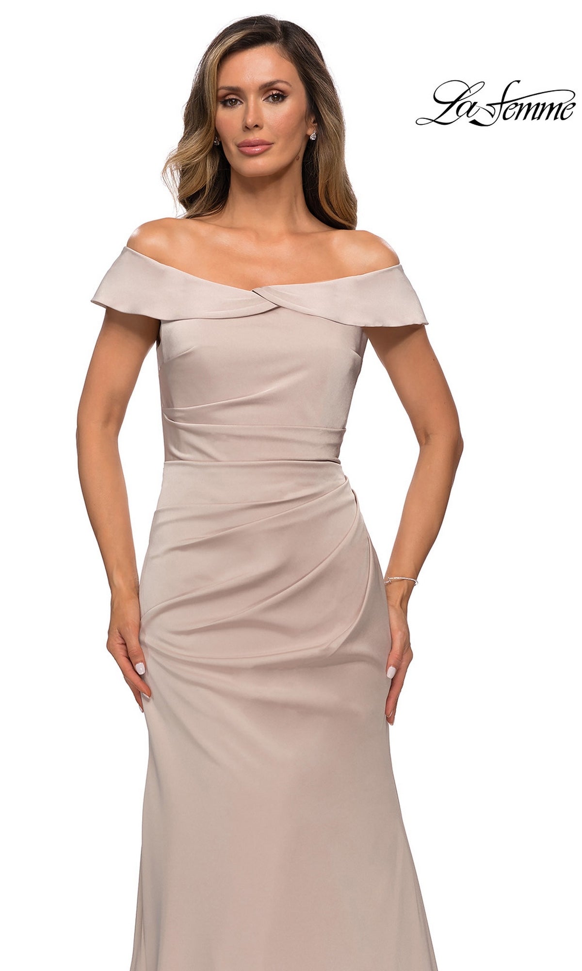 Woman in Long Formal Dress: La Femme 28110, a satin off-the-shoulder gown with ruched waist, poses against a white background; “La Femme” logo at top right.