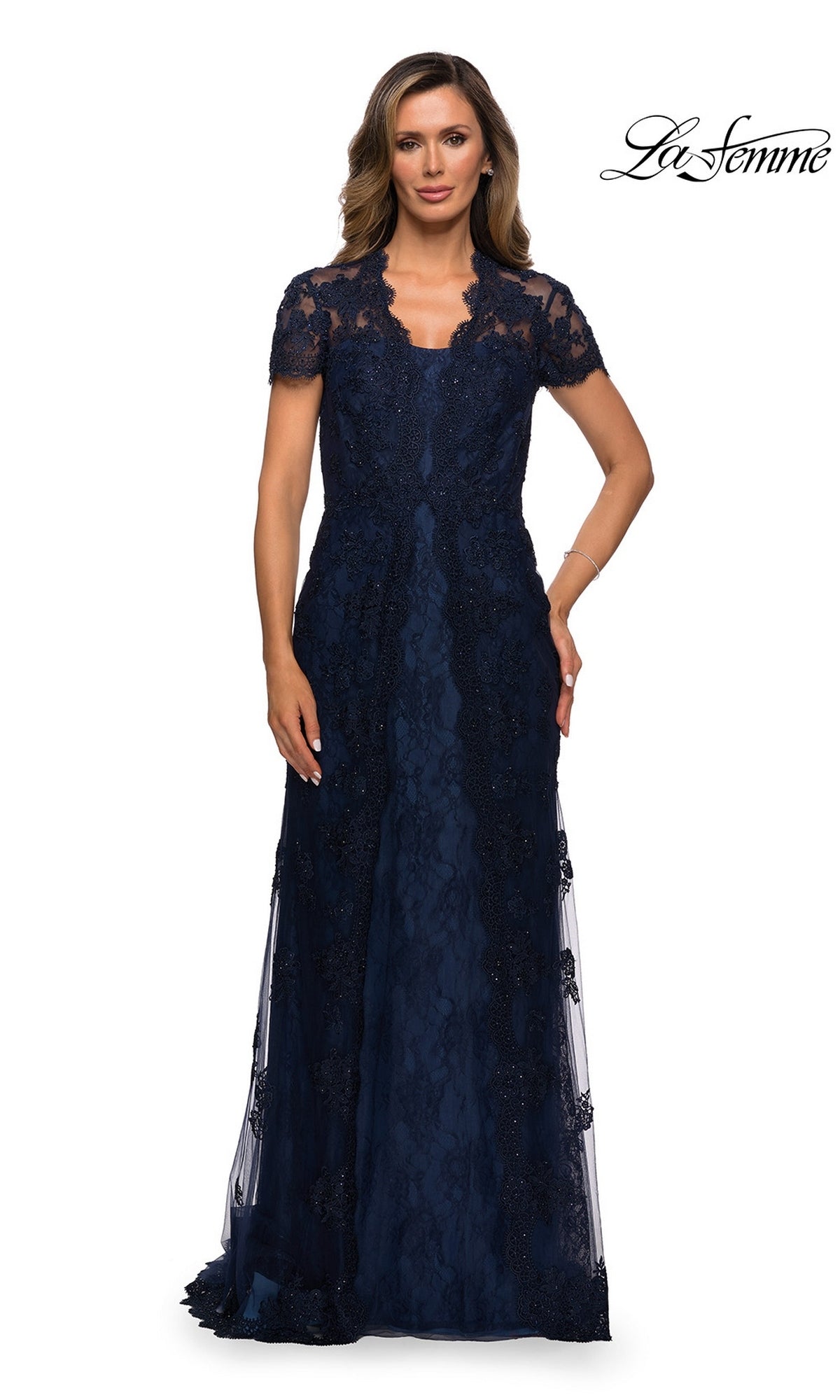 A woman wears a navy Long Formal Dress: La Femme 28195, a long scalloped lace gown with short sleeves and an elegant silhouette.