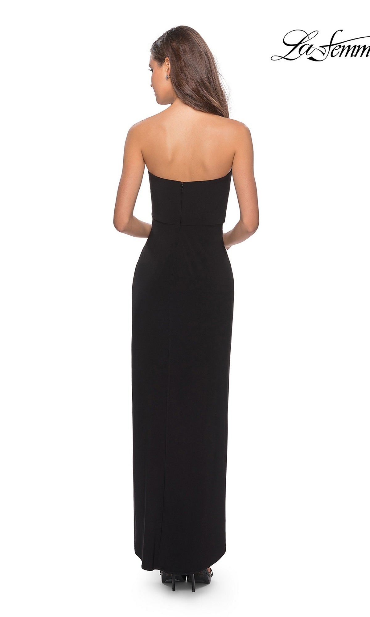 Woman wearing Long Prom Dress: La Femme 28204 with a strapless ruched bodice and sheath skirt, standing and facing away against a white background.