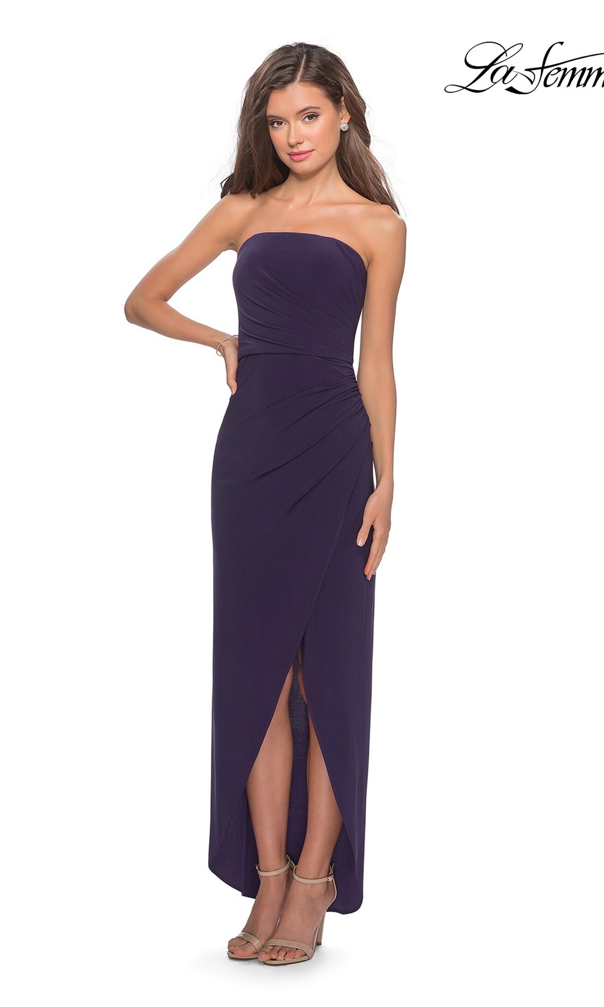 Woman in Long Prom Dress: La Femme 28204, dark purple, strapless with ruched bodice, sheath skirt, and front slit, posing in heels against a white background.