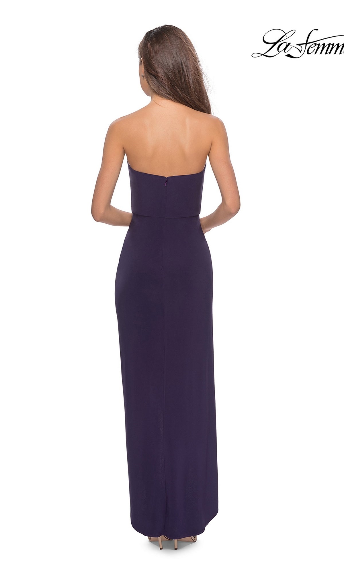 Woman in Long Prom Dress: La Femme 28204, featuring a strapless ruched bodice and sheath skirt in dark purple with high heels, seen from behind on a white background.