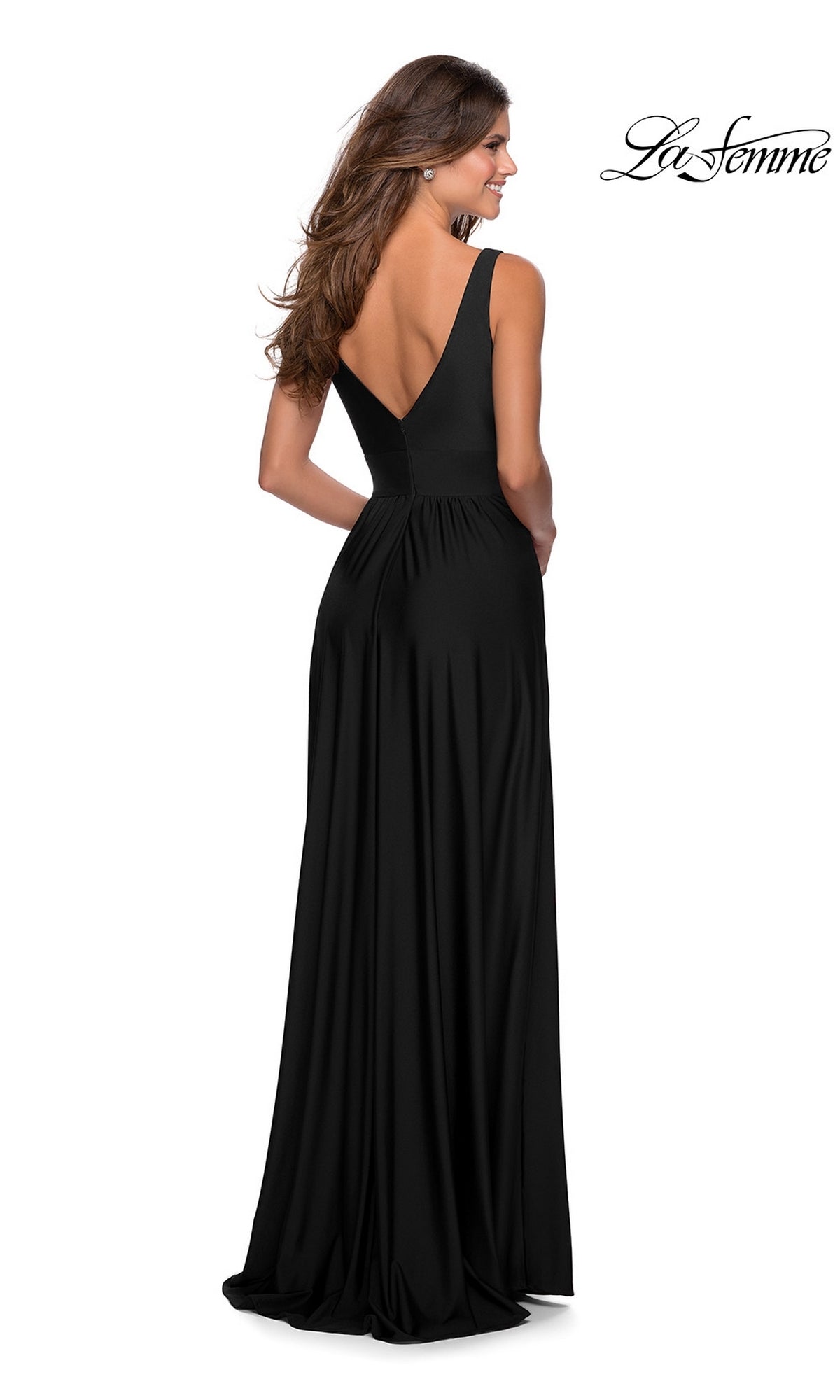 A woman stands facing away from the camera in a floor-length black La Femme Deep V-Neck Long A-Line Prom Dress 28547, featuring a deep V-back and elegant flowing silhouette.