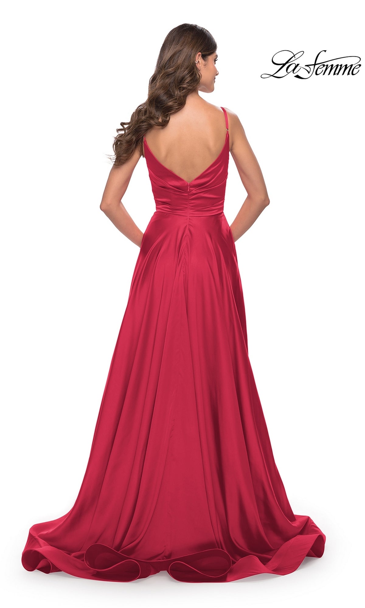 Woman in a sleeveless, floor-length La Femme V-Neck Long A-Line Prom Dress 28607, red satin gown with a V-back, standing facing away on a plain white background.