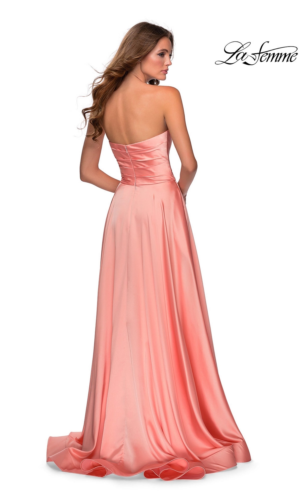 A woman faces away from the camera in a light pink satin La Femme Strapless Long A-Line Prom Dress 28608, featuring a sweetheart neckline and slight train. The La Femme logo is visible in the upper right corner.