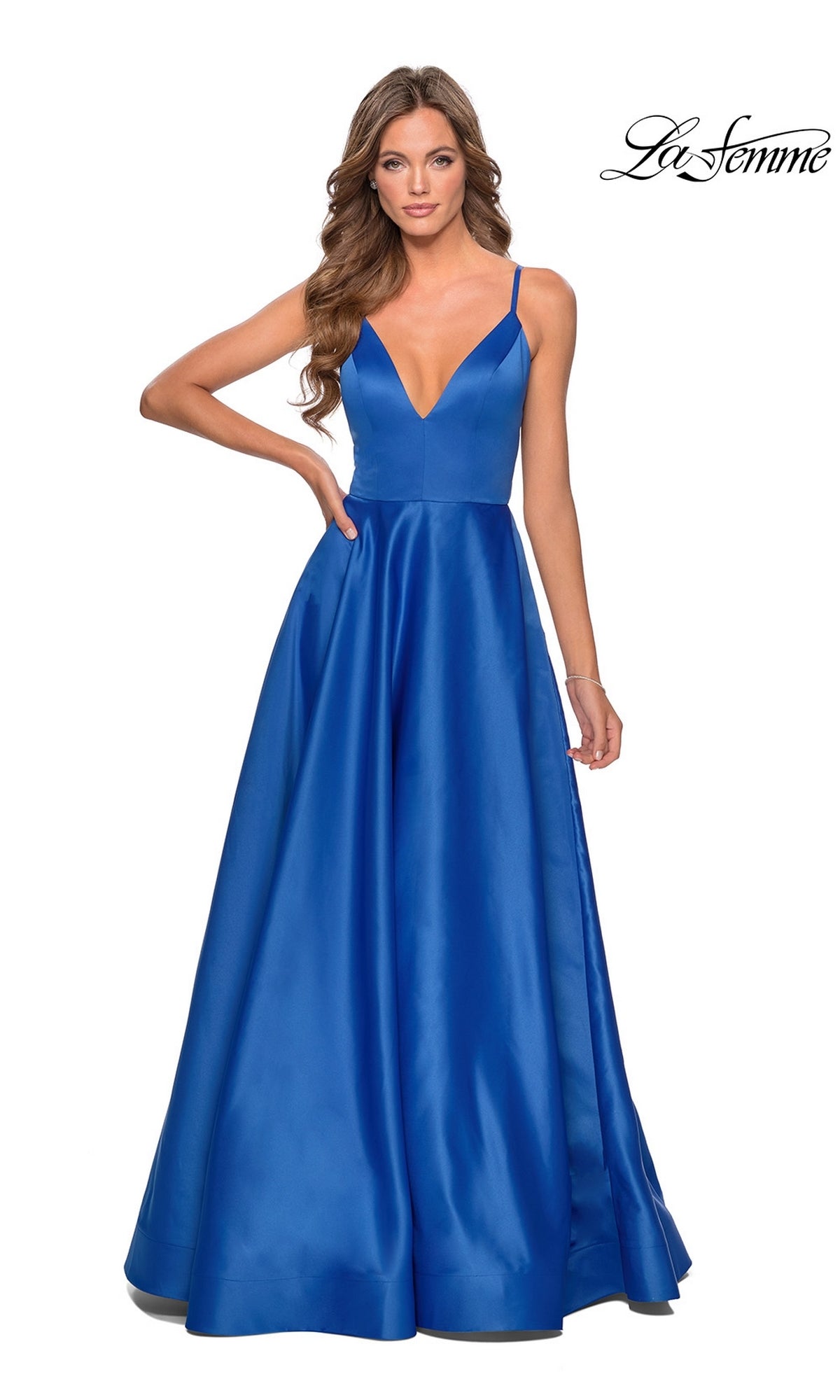 A woman stands against a white background wearing the La Femme Strappy-Back Long A-Line Prom Dress 28628, a sleeveless deep blue satin gown with spaghetti straps and a full skirt.