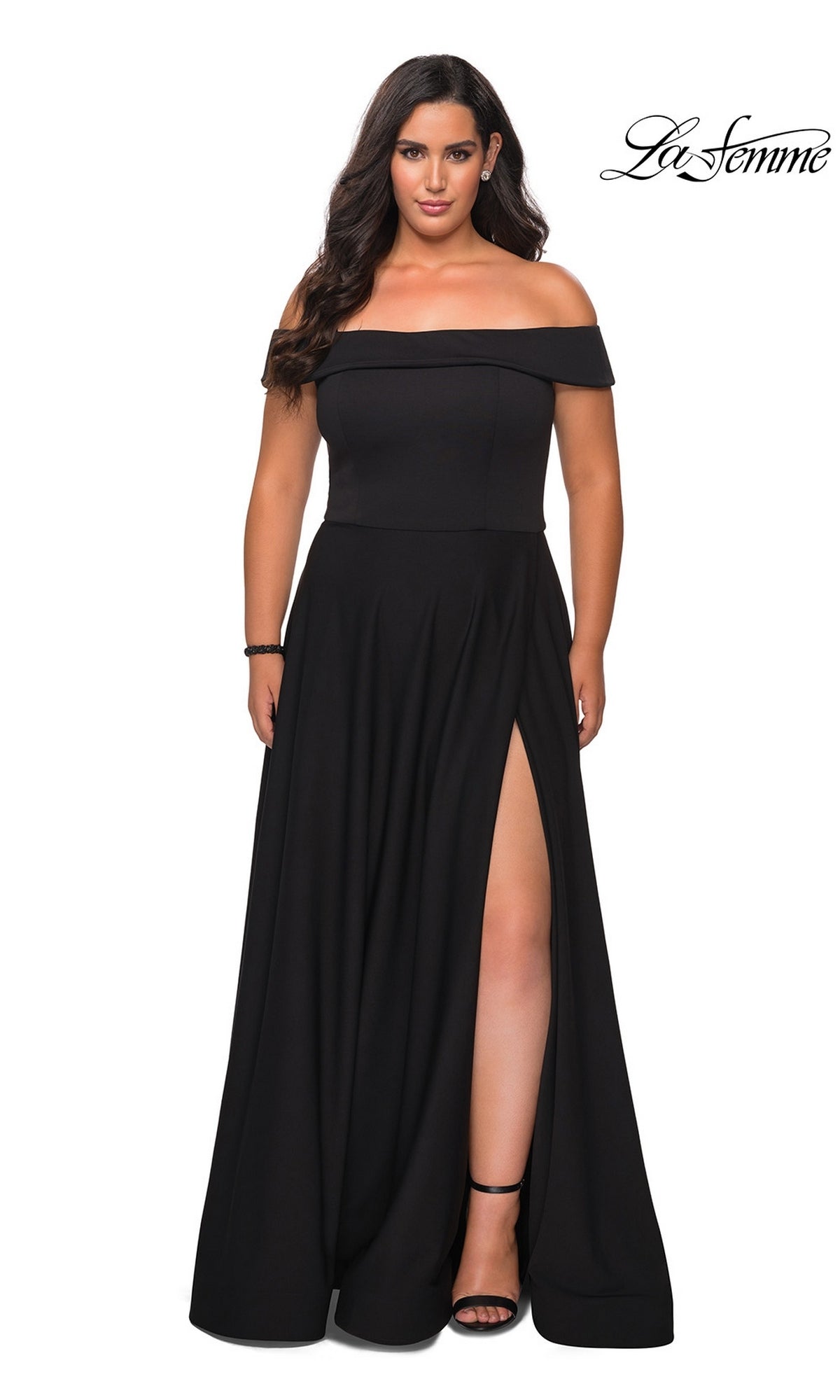 Woman in the Long Plus-Size Prom Dress: La Femme 29007, black, with a thigh-high slit and off-the-shoulder design, black heels and bracelet, on a white background.