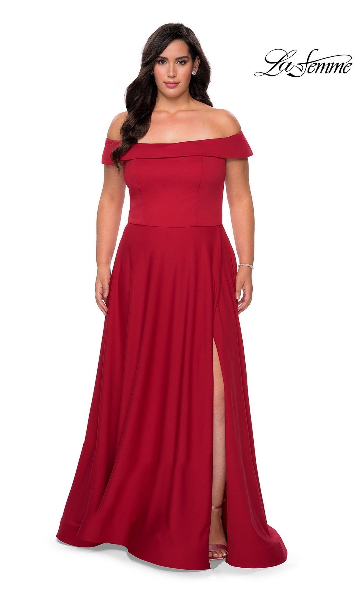 A woman wears the Long Plus-Size Prom Dress: La Femme 29007 in red, featuring off-the-shoulder style and a thigh-high slit, standing against a plain white background.