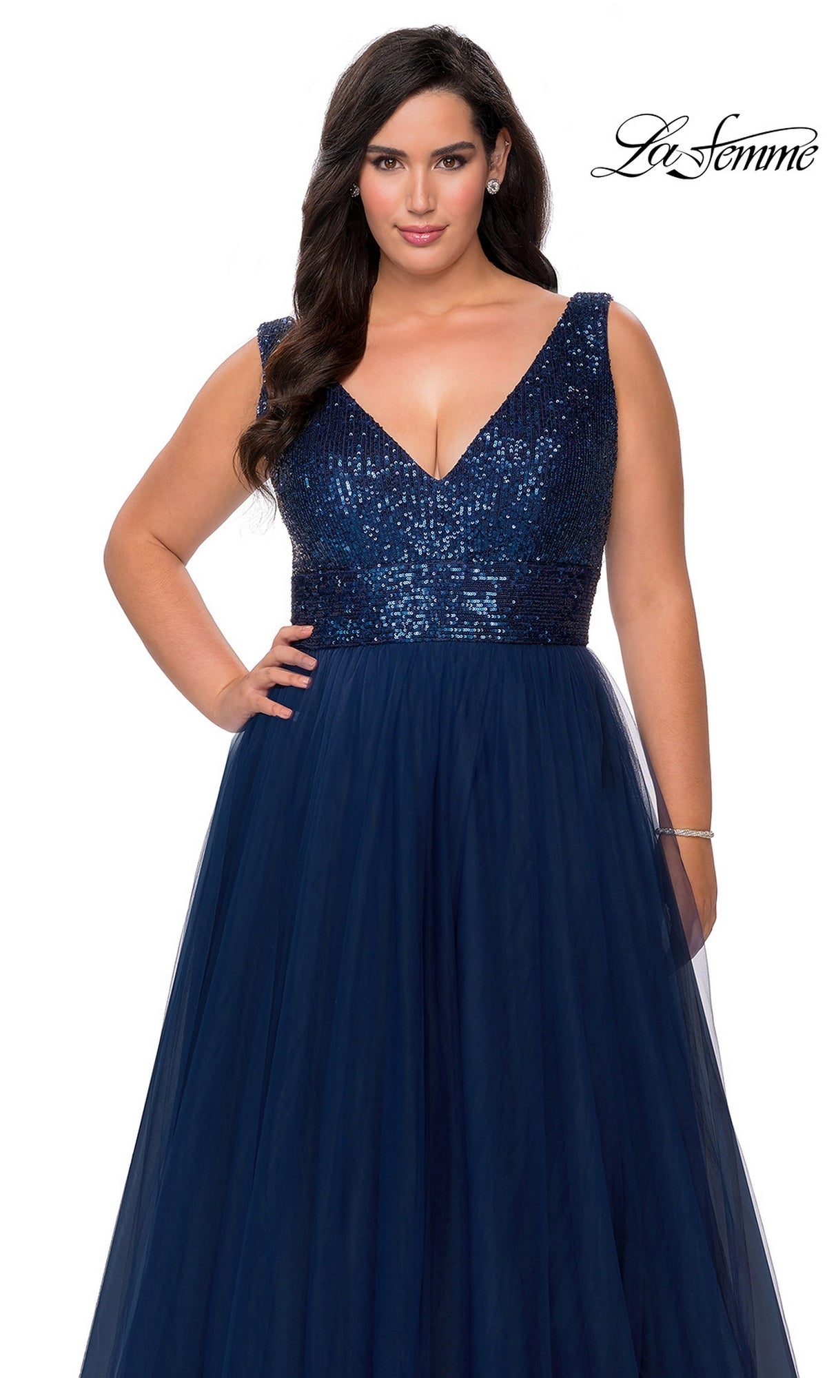 A woman models the Long Plus-Size Prom Dress: La Femme 29045 with a sequin bodice and tulle A-line skirt against a white background.