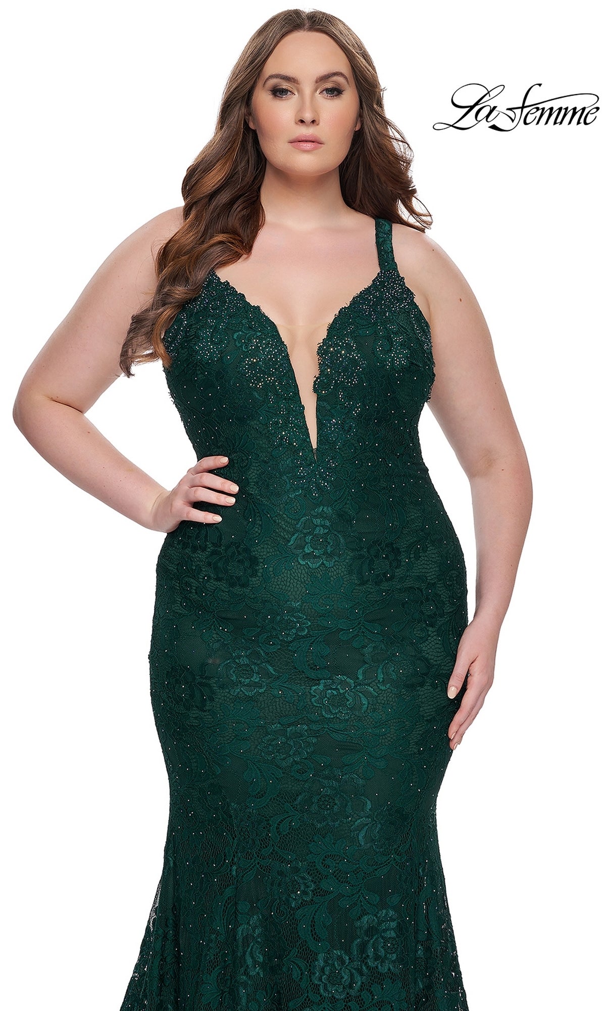 A woman models the La Femme Long Prom Dress 29052—a fitted dark green floral lace gown with a deep V-neckline and beaded details—standing before a white background. The La Femme logo appears in the top right corner.