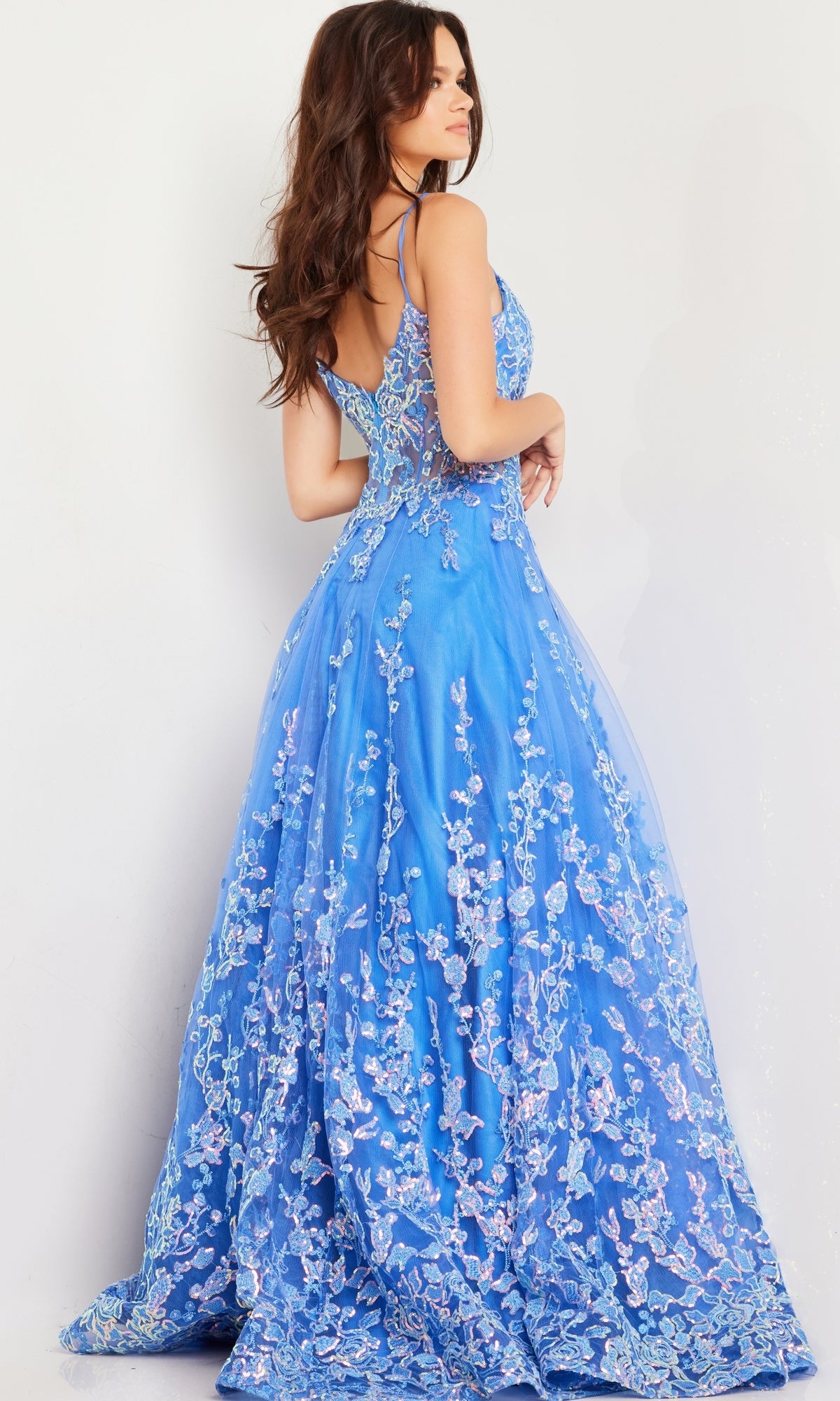A woman, seen from behind with loose wavy hair, wears the Long Prom Dress 29072 by Jovani—a turquoise blue gown with floral sequin embroidery and thin shoulder straps.