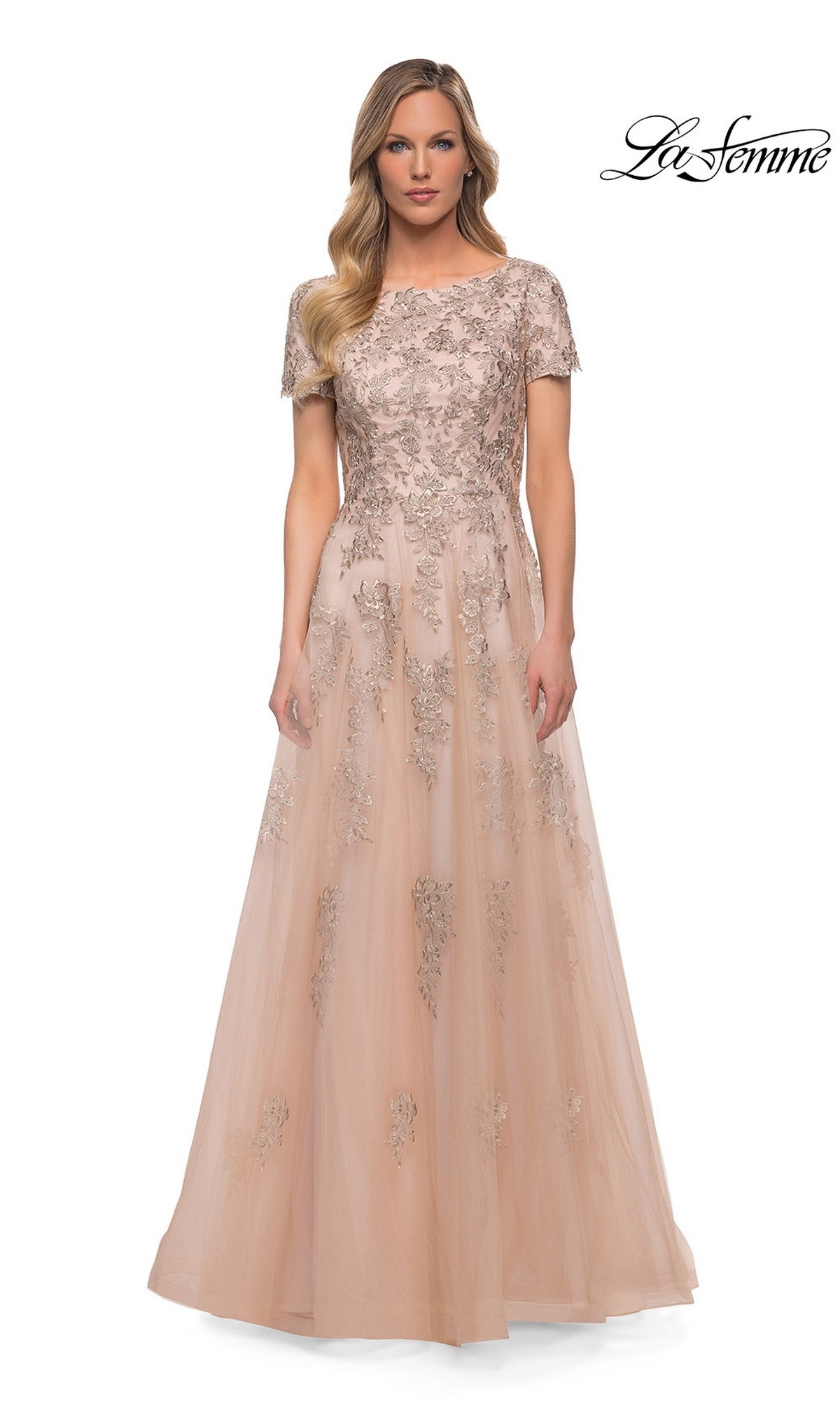 Woman in a floor-length, short-sleeve nude tulle Long Formal Dress: La Femme 29290 with silver floral embroidery, standing against a white background. “La Femme” logo in top right.