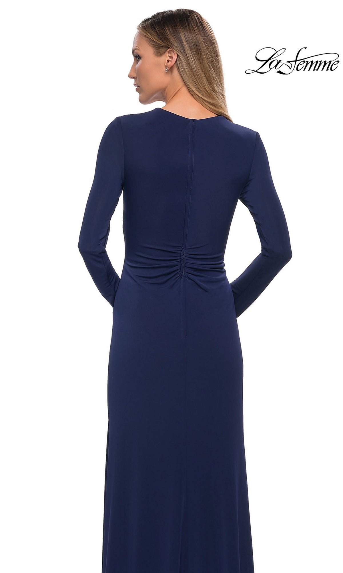 A woman seen from the back wearing a navy blue, long-sleeve, floor-length La Femme 29535 gown with ruched detailing at the lower back.