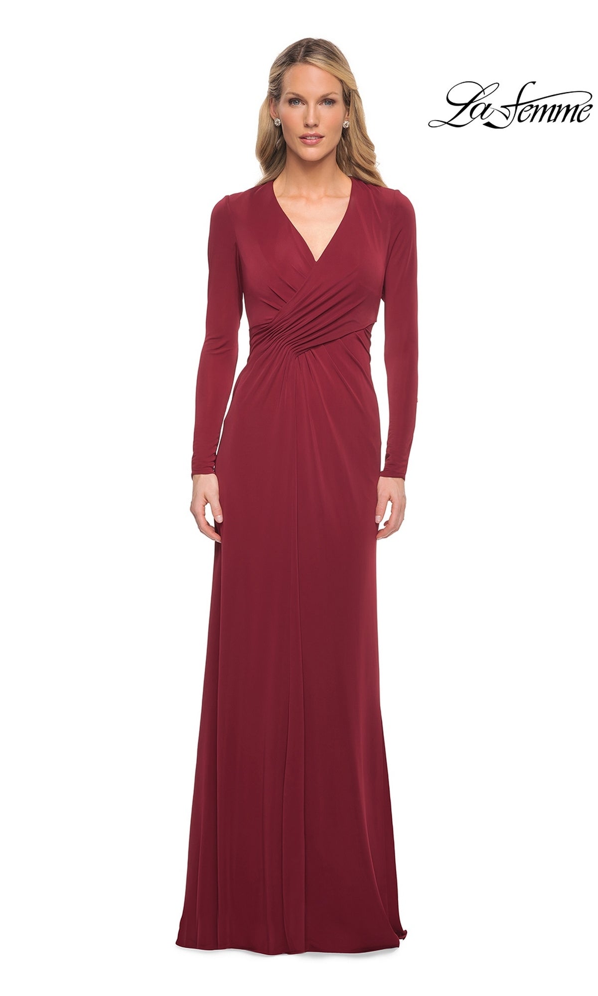 A woman wears a wine-colored La Femme 29535 long-sleeve formal dress featuring a floor-length V-neck silhouette and ruched waist detail.