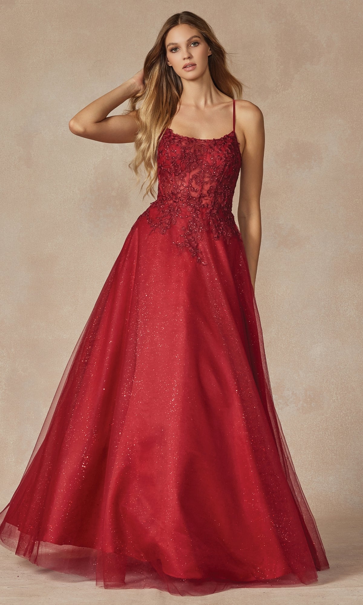 A woman wearing the Lace-Up Long A-Line Prom Dress: Juliet 295, featuring thin straps, a lace bodice, and a full tulle skirt in red, stands against a neutral background.