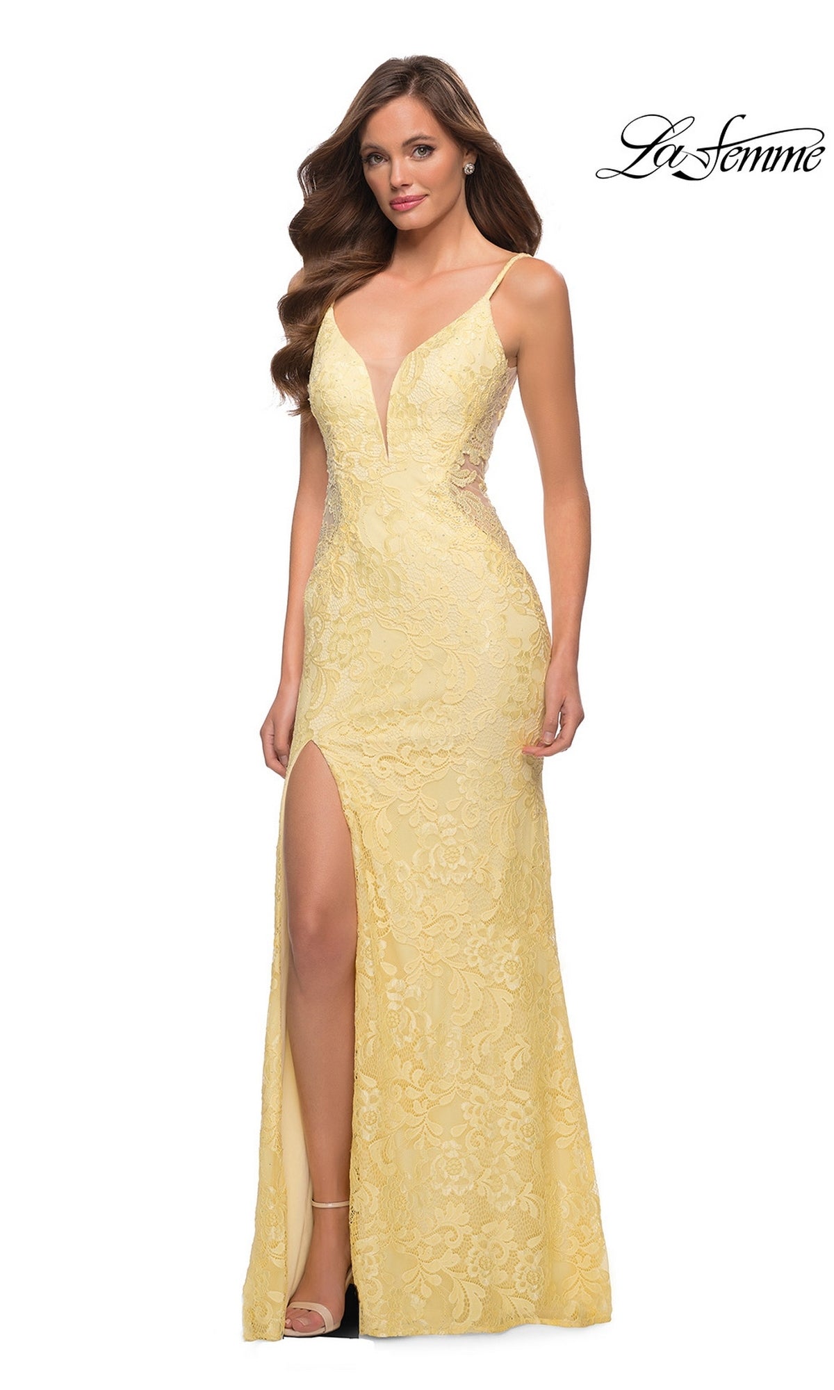 A woman wears the pale yellow Long Prom Dress: La Femme 29679, a floor-length stretch-lace gown with a deep V-neckline, spaghetti straps, and a high side slit.