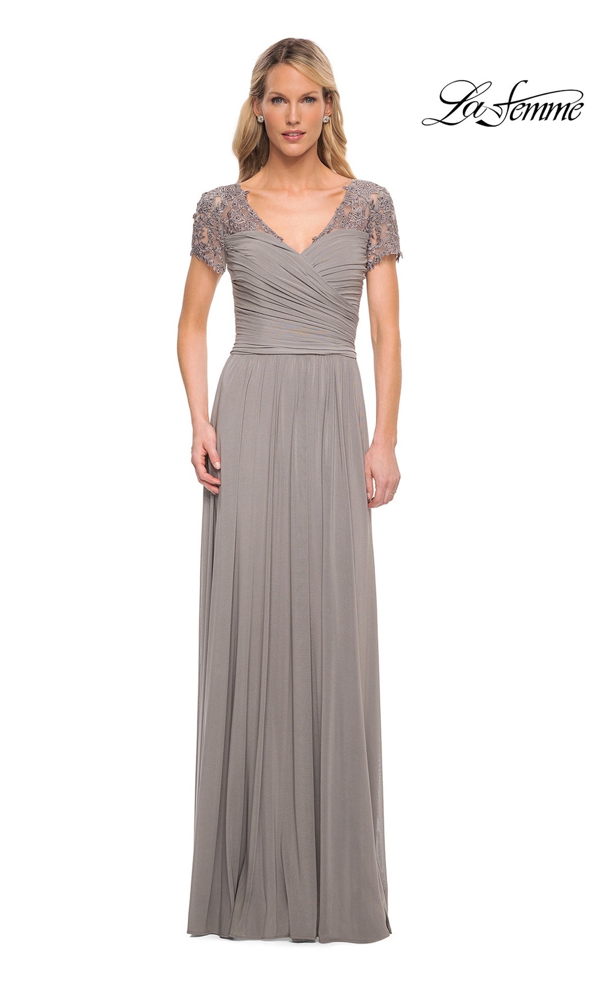 A woman in the Long Formal Dress: La Femme 29772 in silver, featuring lace short sleeves and a ruched fitted bodice, stands against a white background.