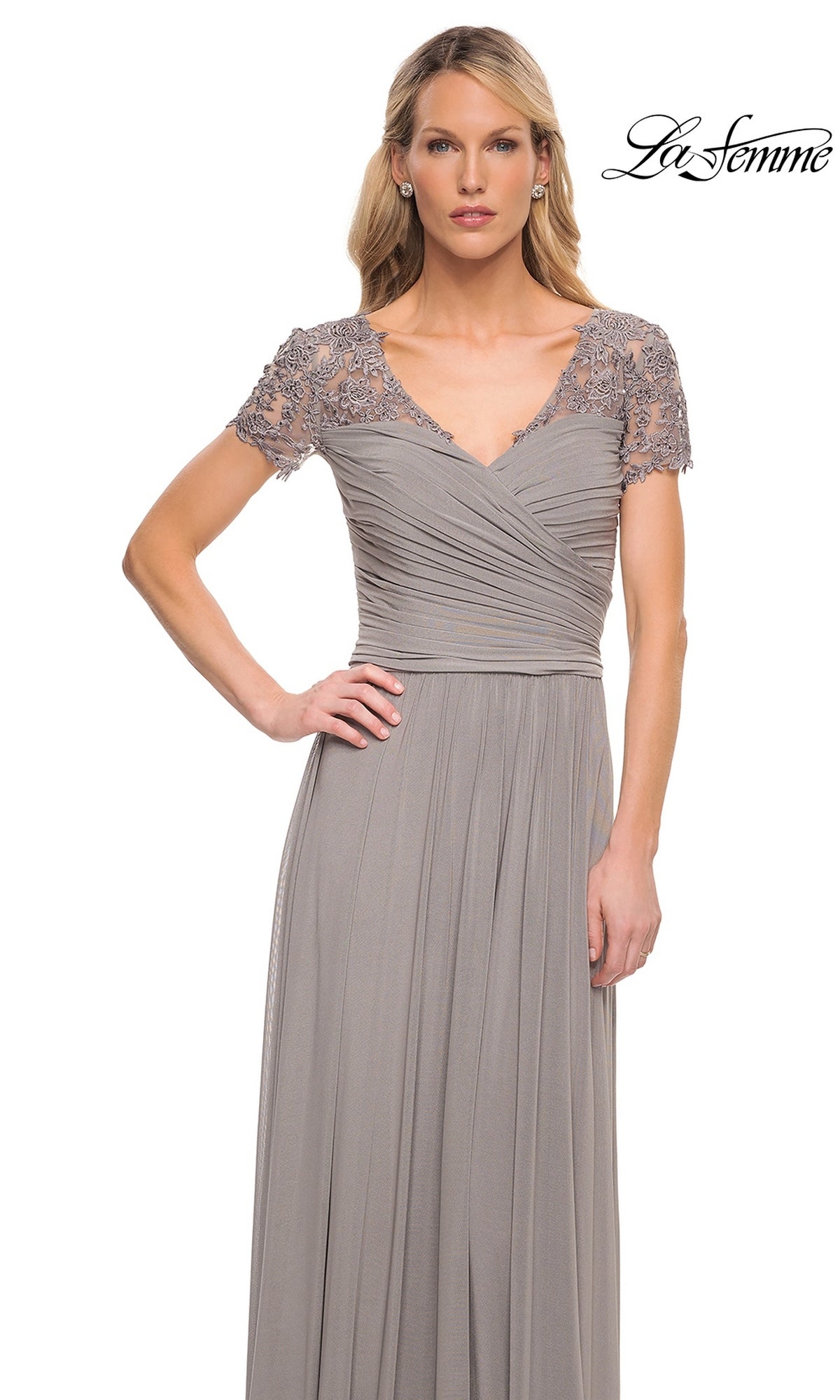A woman wears the Long Formal Dress: La Femme 29772, a floor-length gray gown with an A-line skirt, lace shoulders, and a ruched fitted bodice, against a white background.