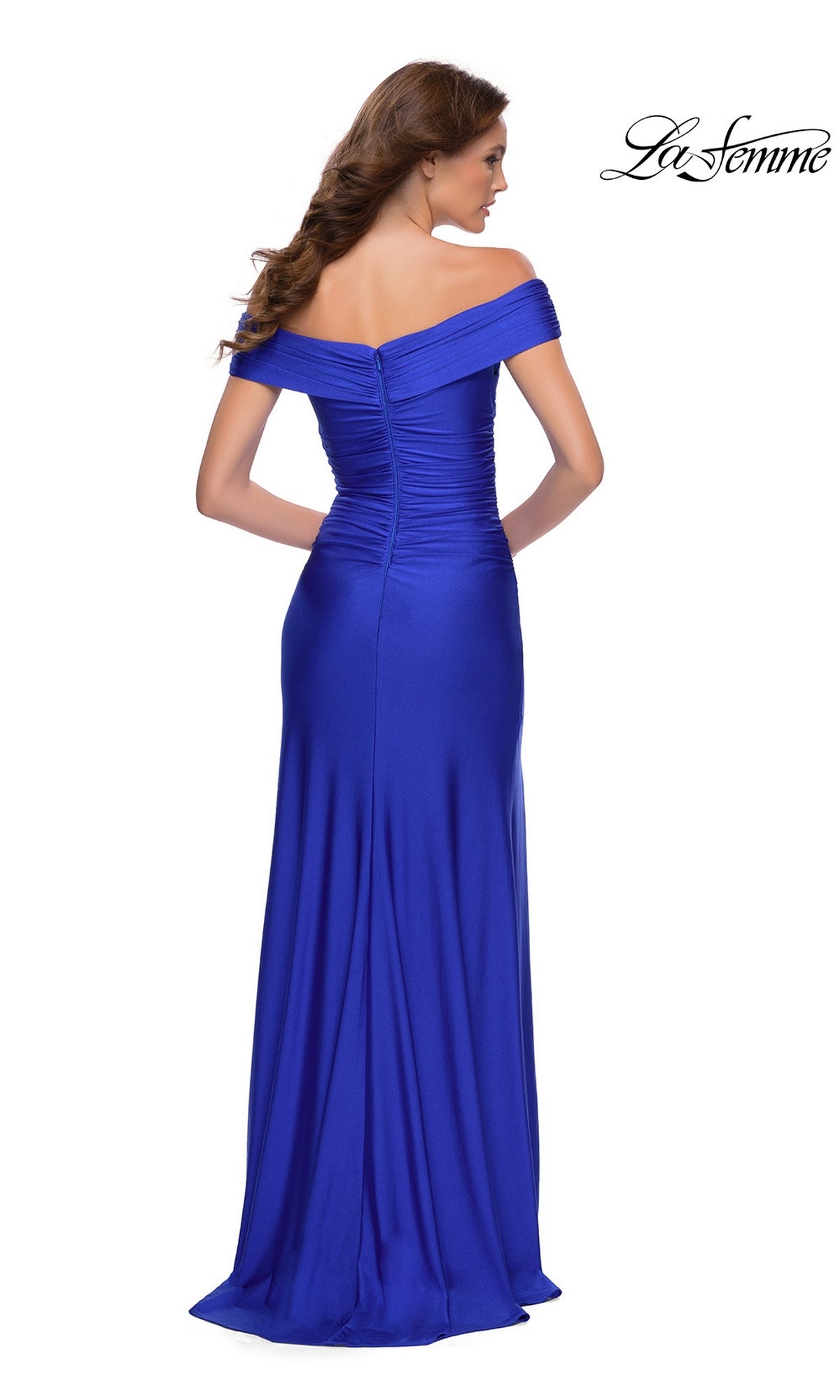 A woman elegantly photographed from the back wears the La Femme Long Prom Dress 29781, a floor-length royal blue off-the-shoulder gown with ruched detailing.