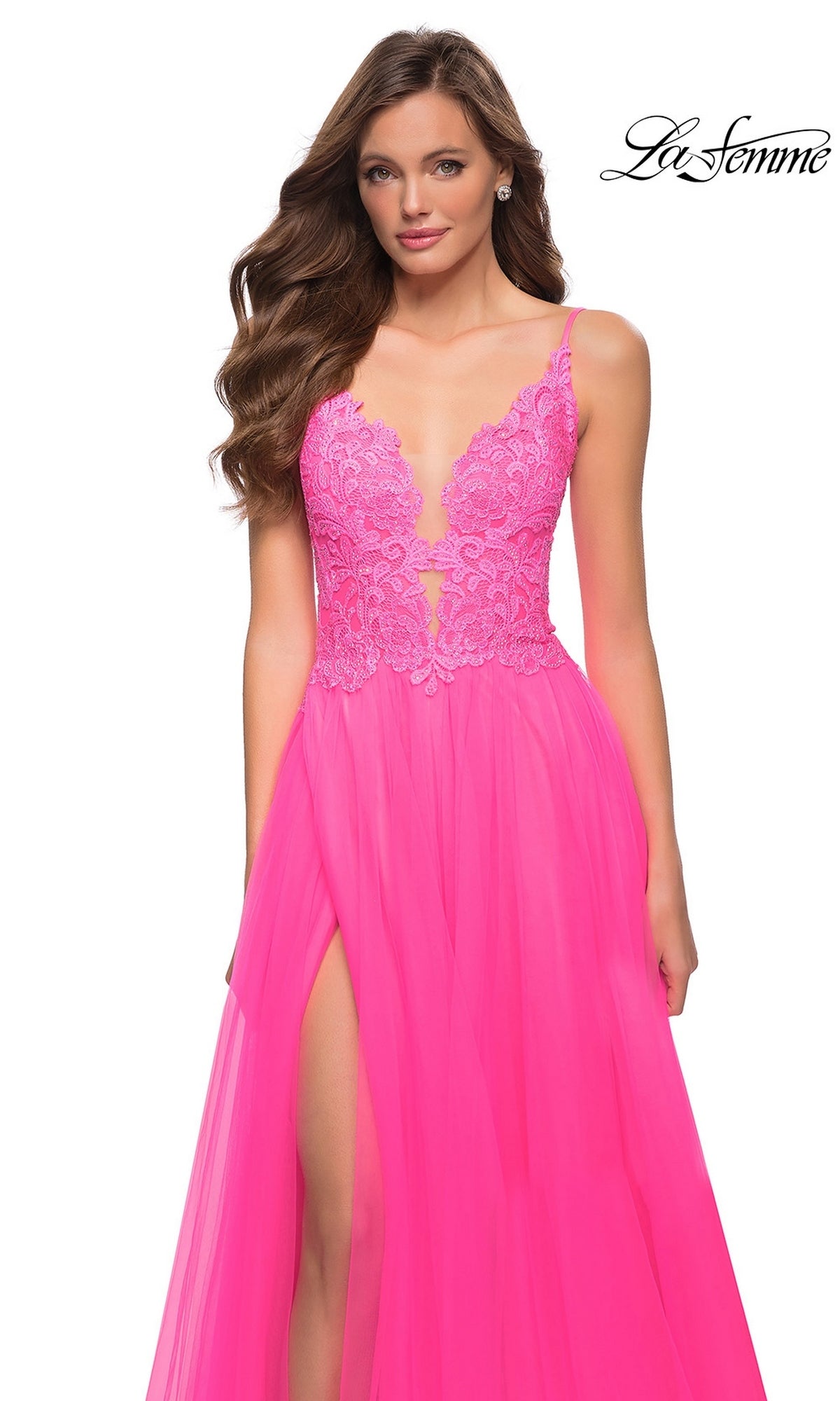 A woman wears a neon pink Long Prom Dress: La Femme 29964, a sleeveless A-line gown with a lace bodice, deep V-neckline, and high side slit.