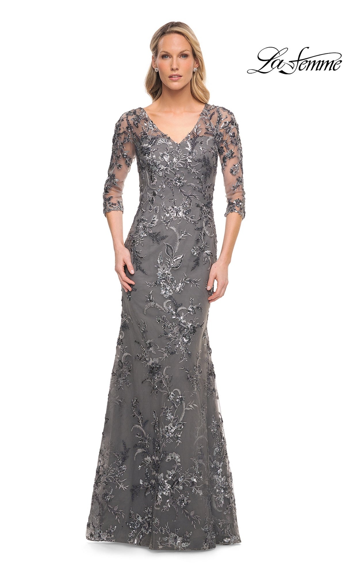 A woman in a gunmetal La Femme 29976 floor-length V-neck gown with three-quarter sleeves and floral beaded appliques.