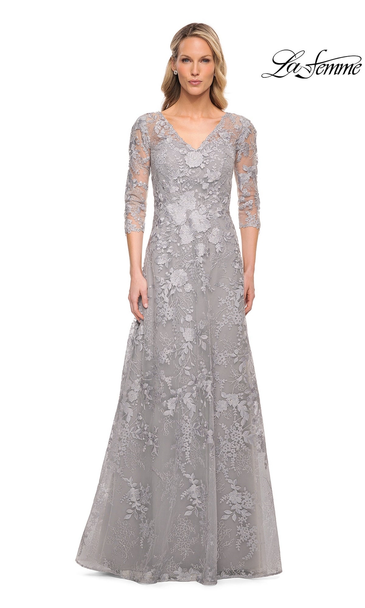 A woman wears a silver, floor-length V-neck Long Formal Dress: La Femme 29989 with three-quarter sleeves and floral lace embroidery.