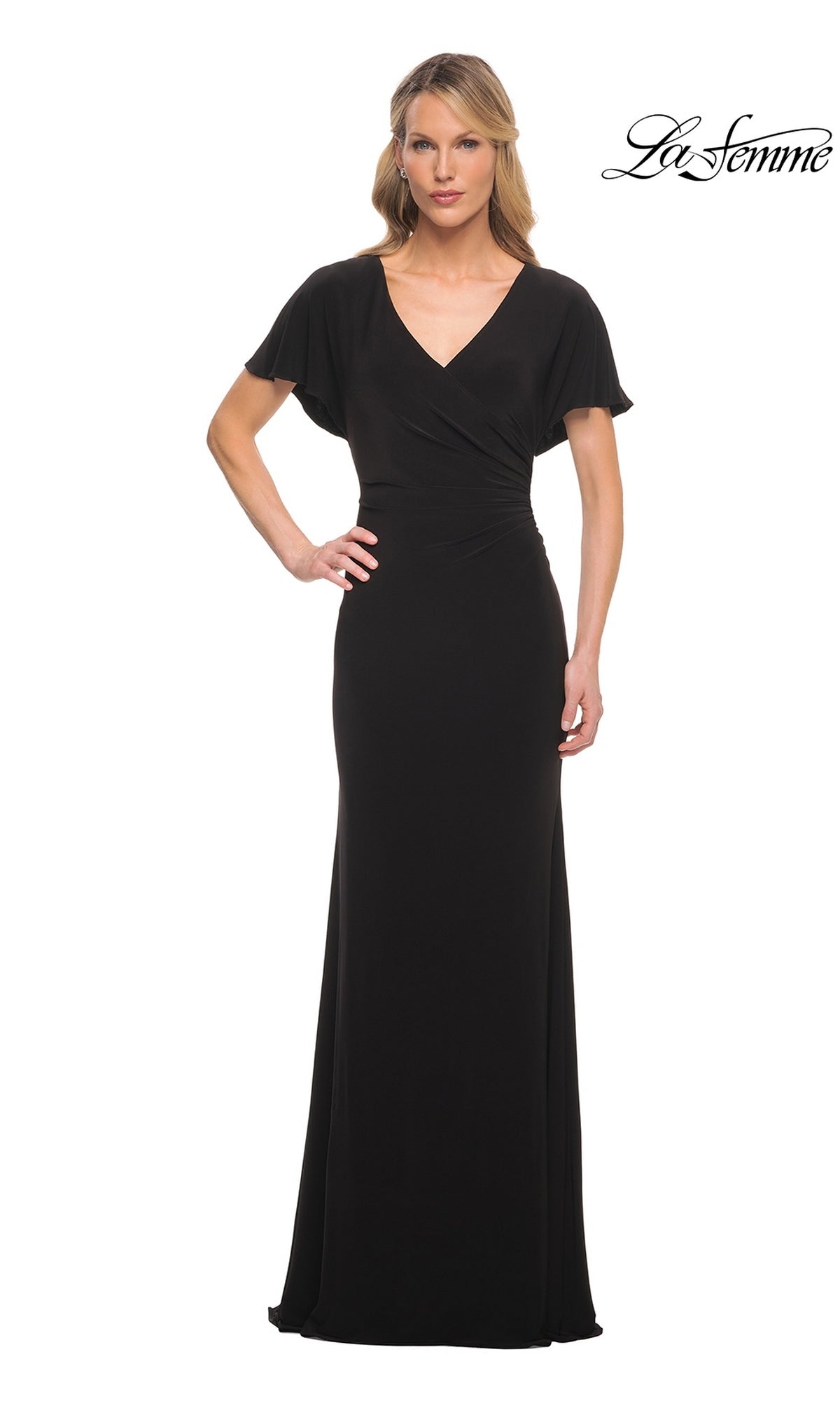 A woman wears a black Long Formal Dress: La Femme 29997, a floor-length jersey gown featuring a V-neckline and flutter sleeves.