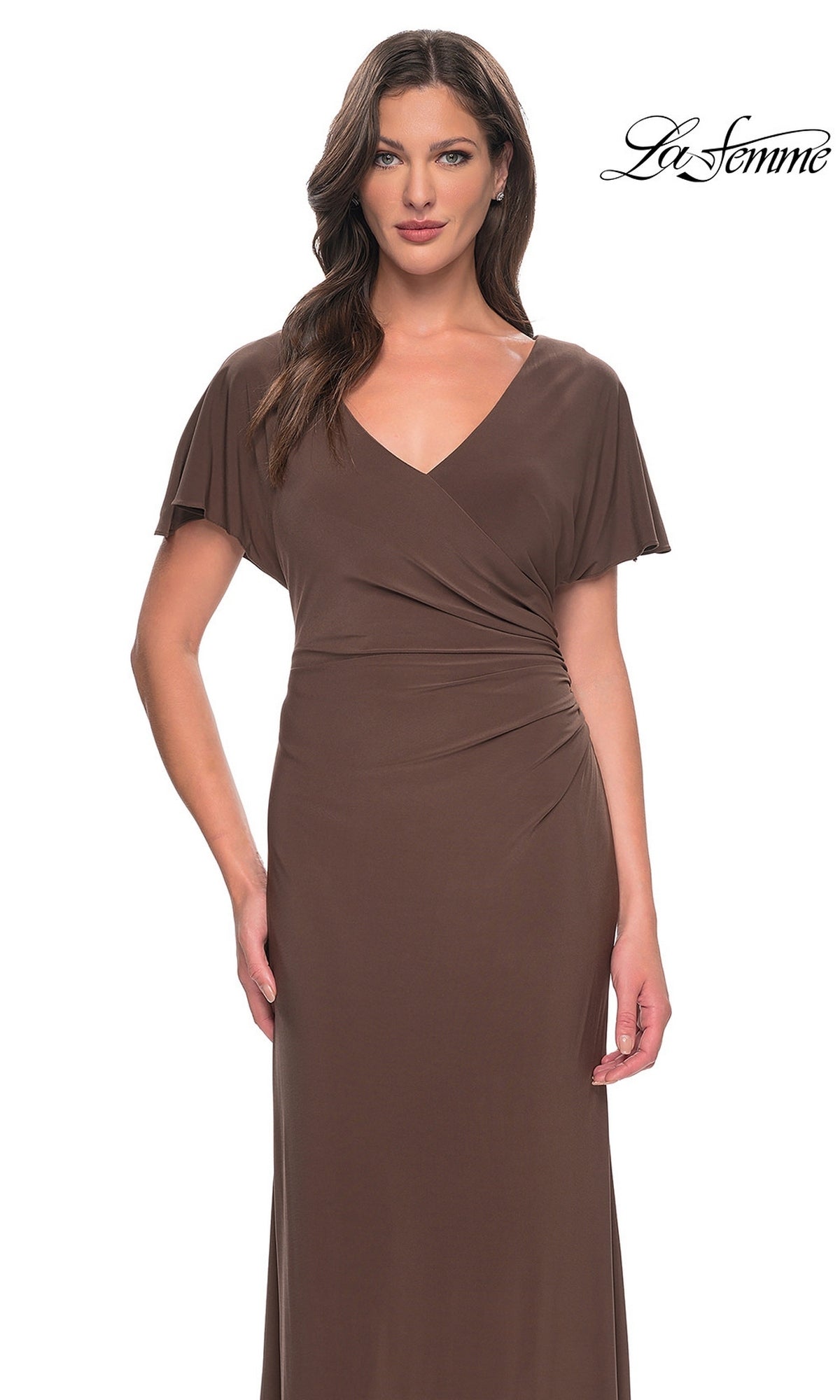 A woman wears a brown Long Formal Dress: La Femme 29997, a V-neck floor-length gown featuring short flutter sleeves, a sheath skirt, and ruched detailing at the waist.